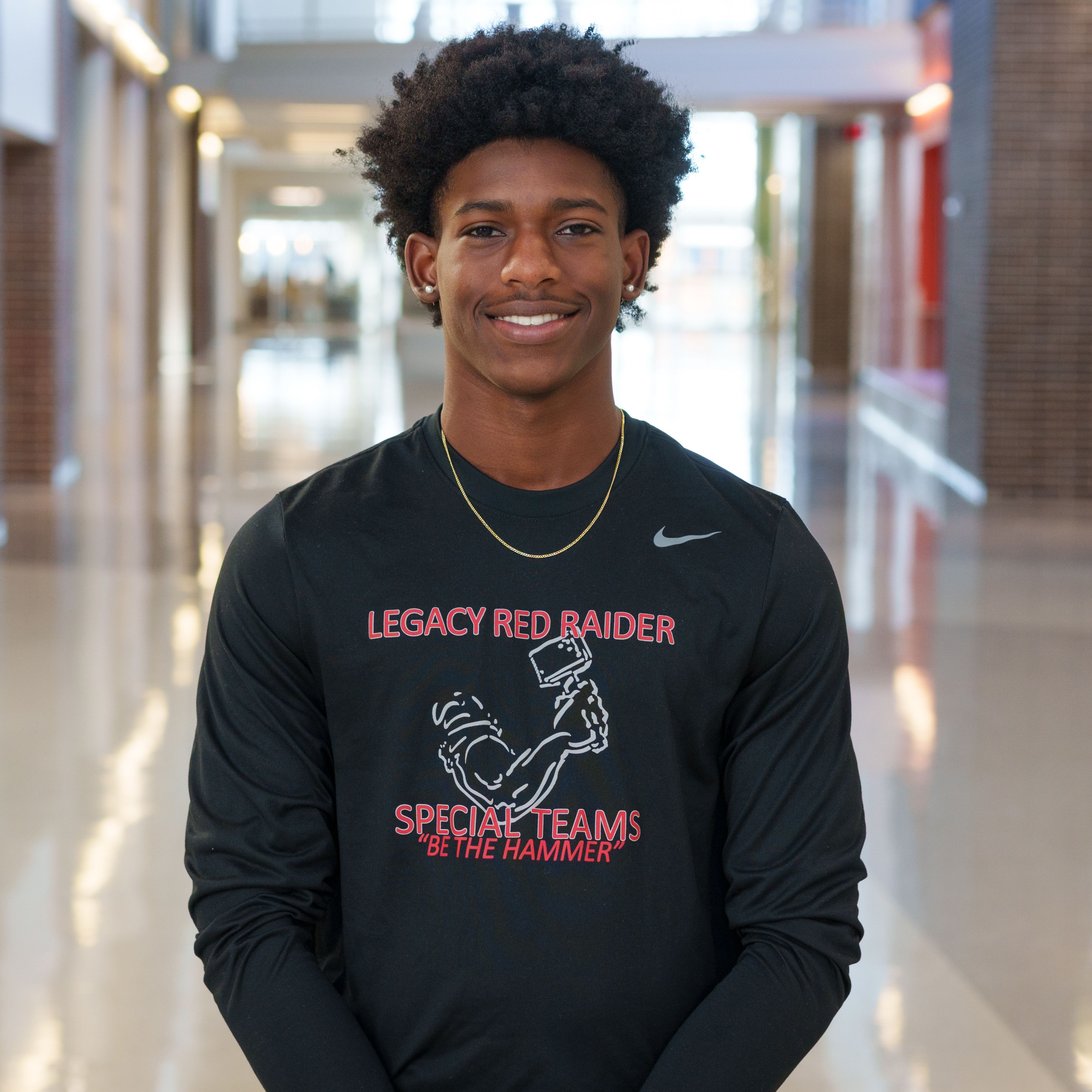 high school boy wearing black t-shirt standing in school hallway