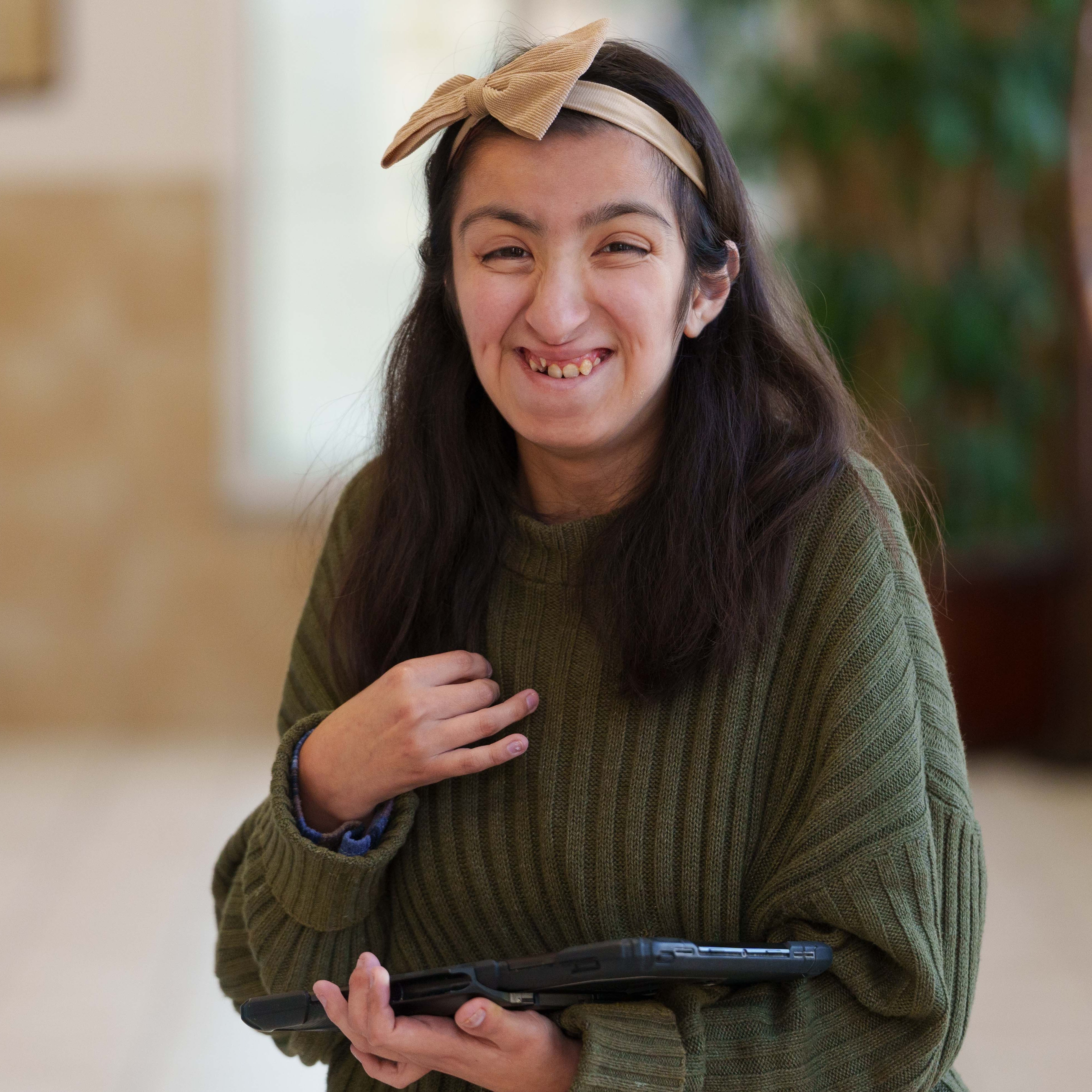 high school boy wearing green sweater holding an ipad