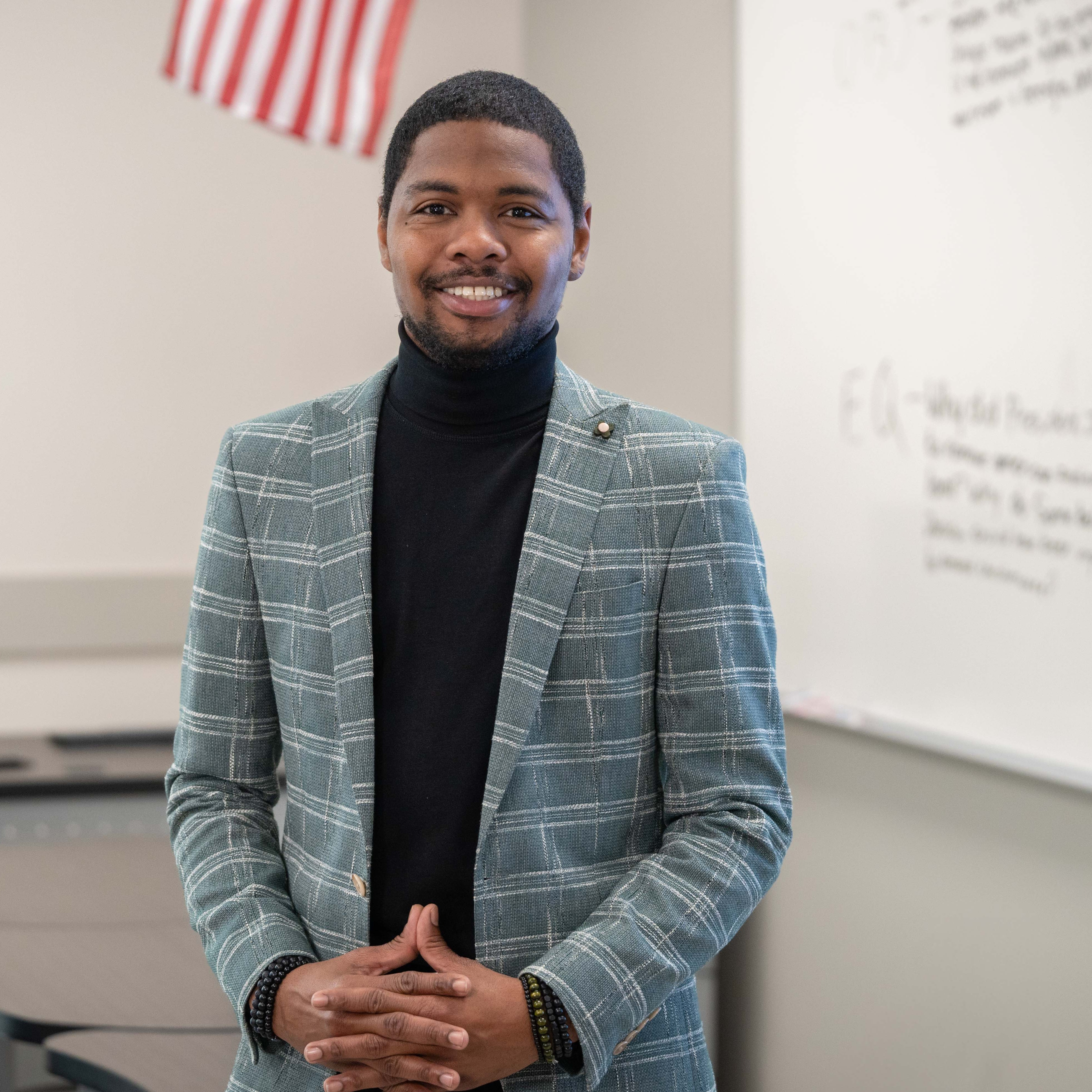 man wearing plaid jacket standing in classroom