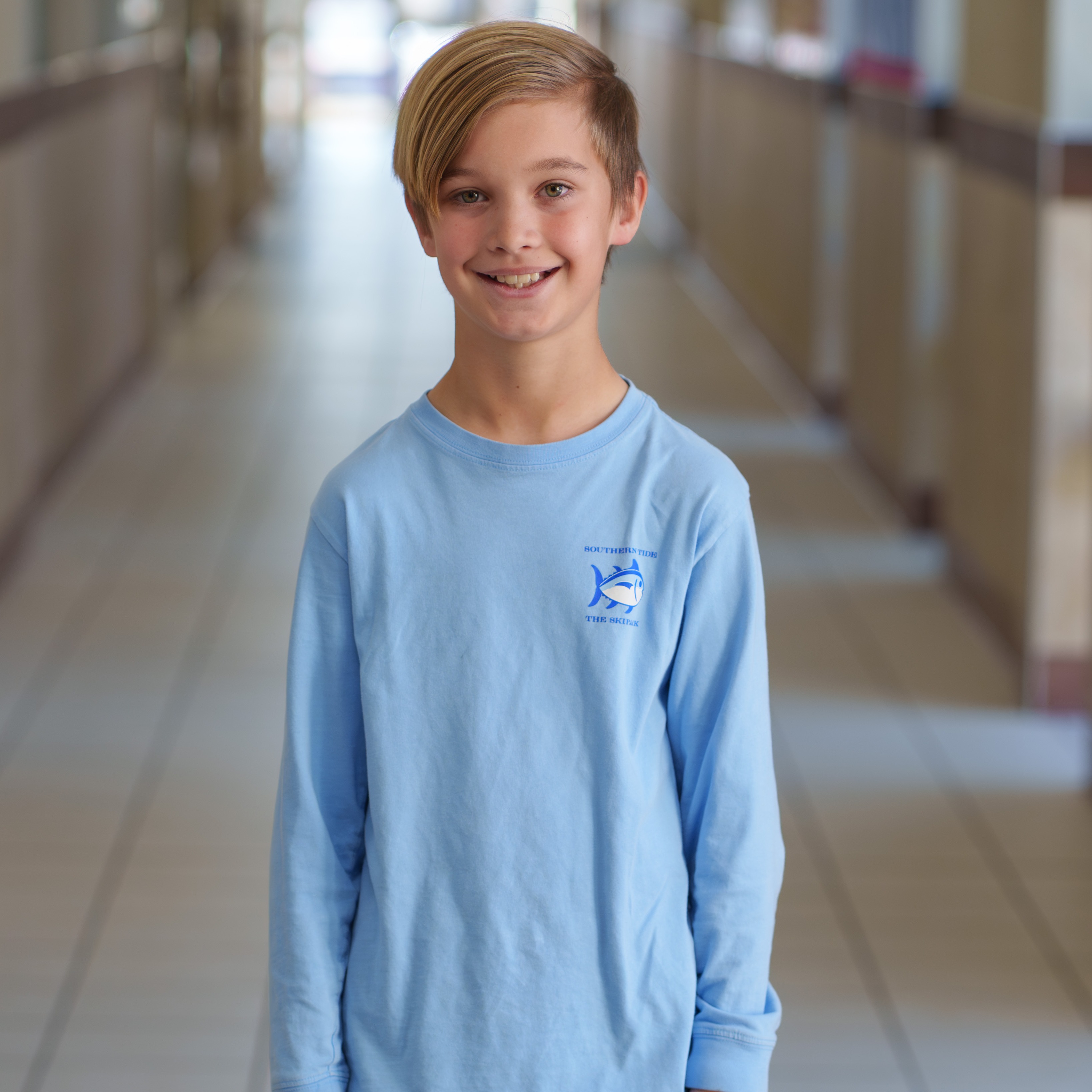 elementary age boy wearing blue shirt standing in hallway