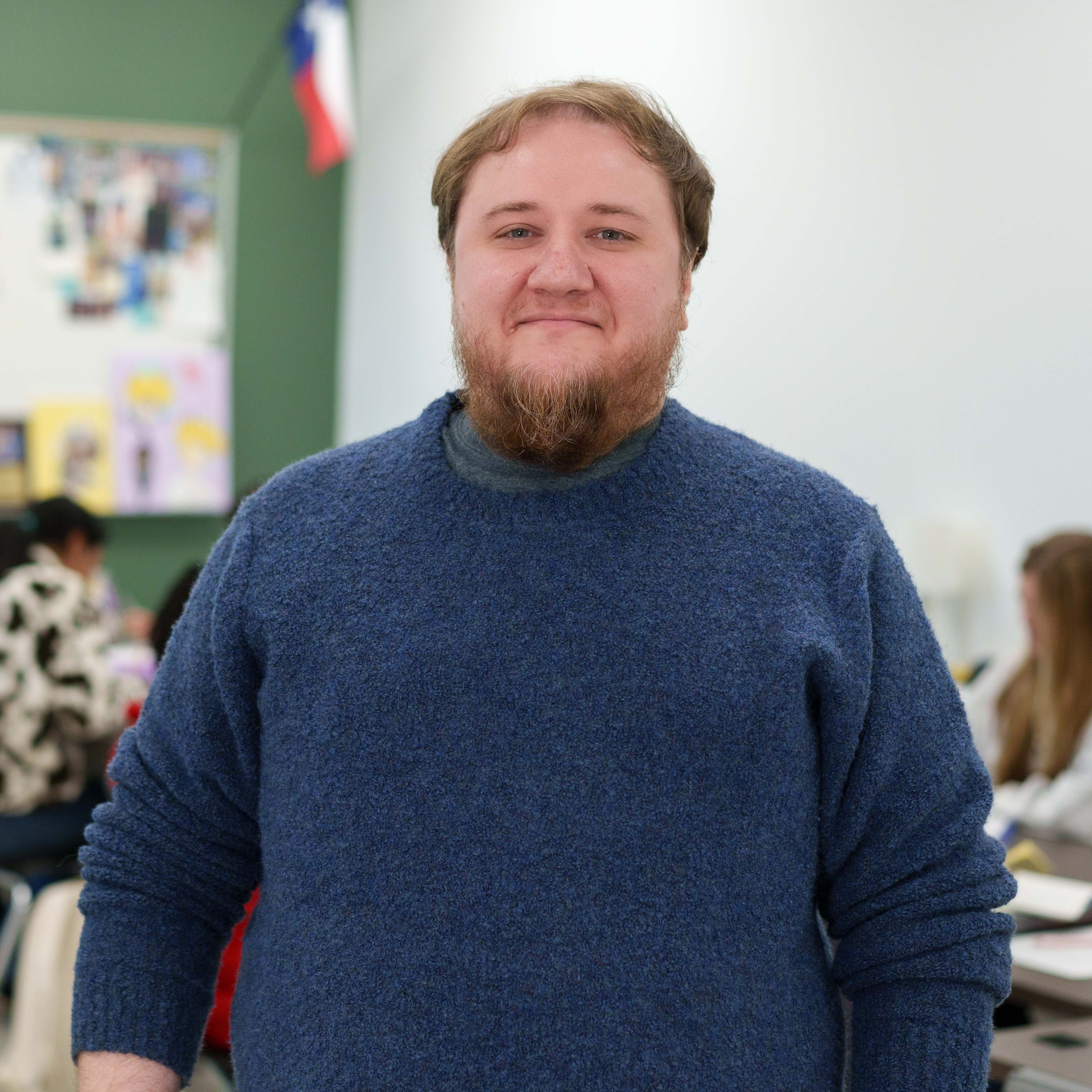 Caucasian man wearing blue shirt standing in classroom