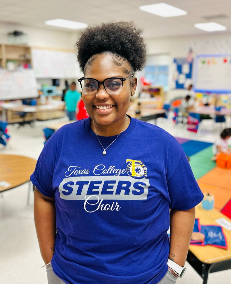 woman in blue tshirt standing in classroom