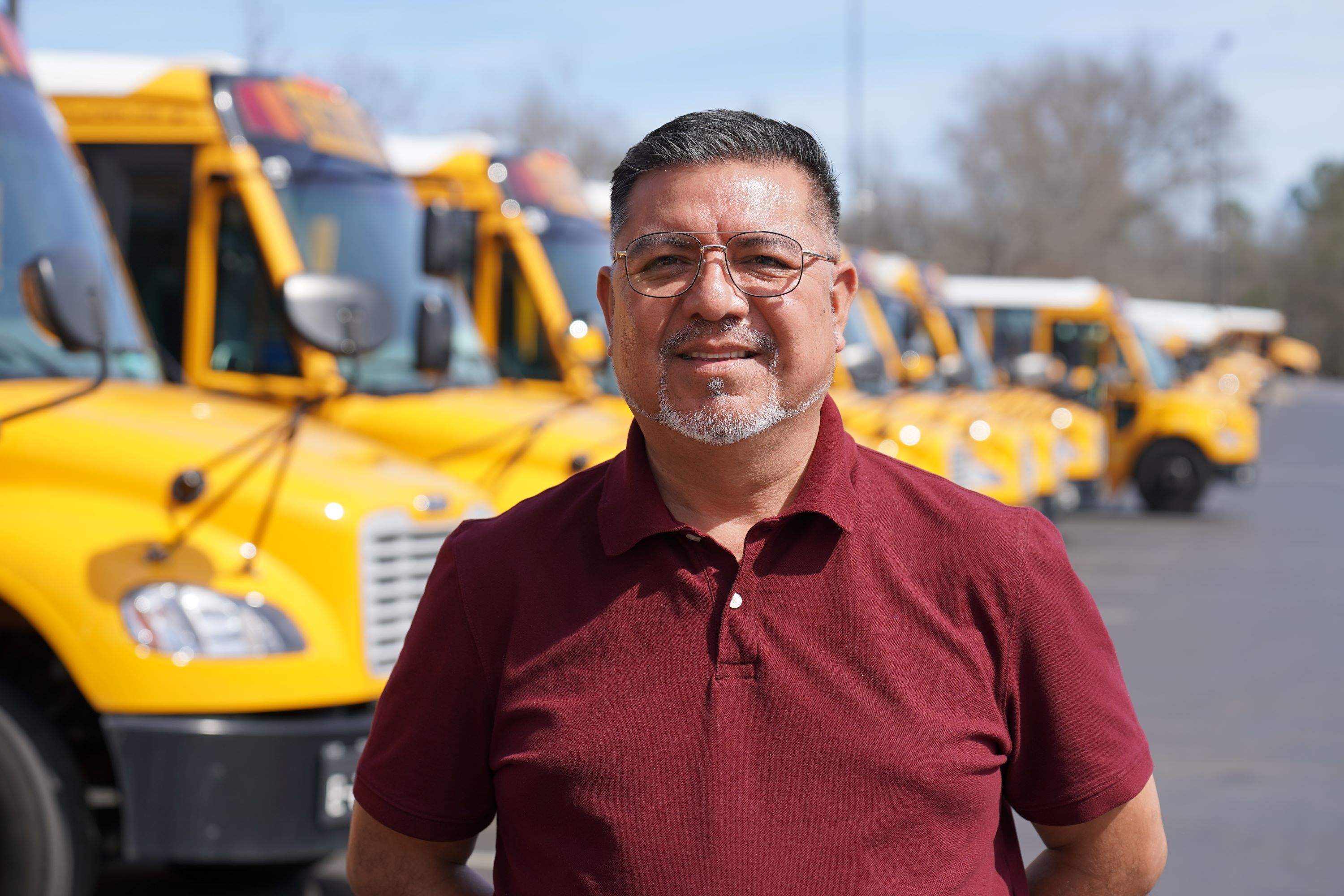 Hispanic man standing in front of row of buses