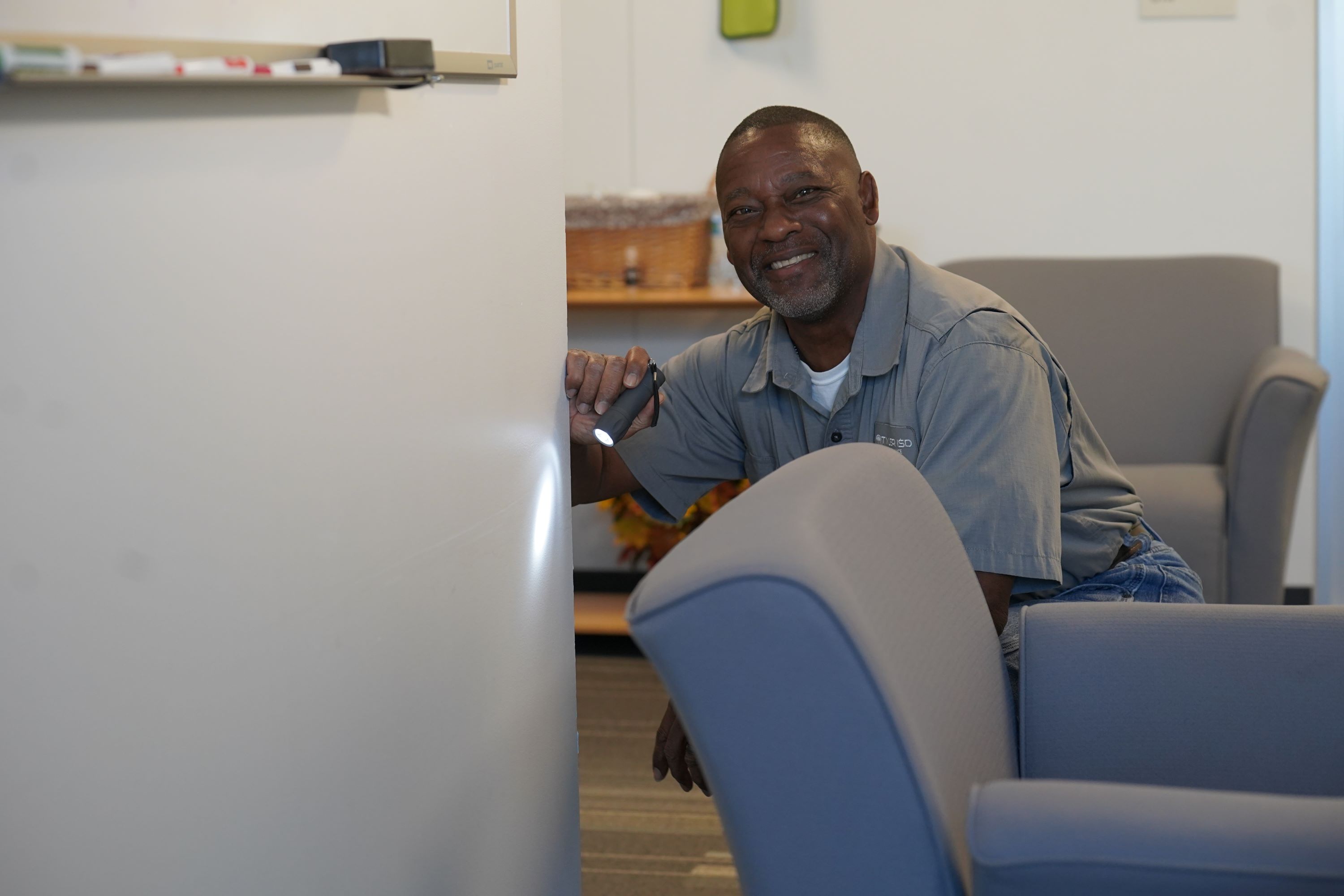 African American man shining flashlight on a wall behind a chair