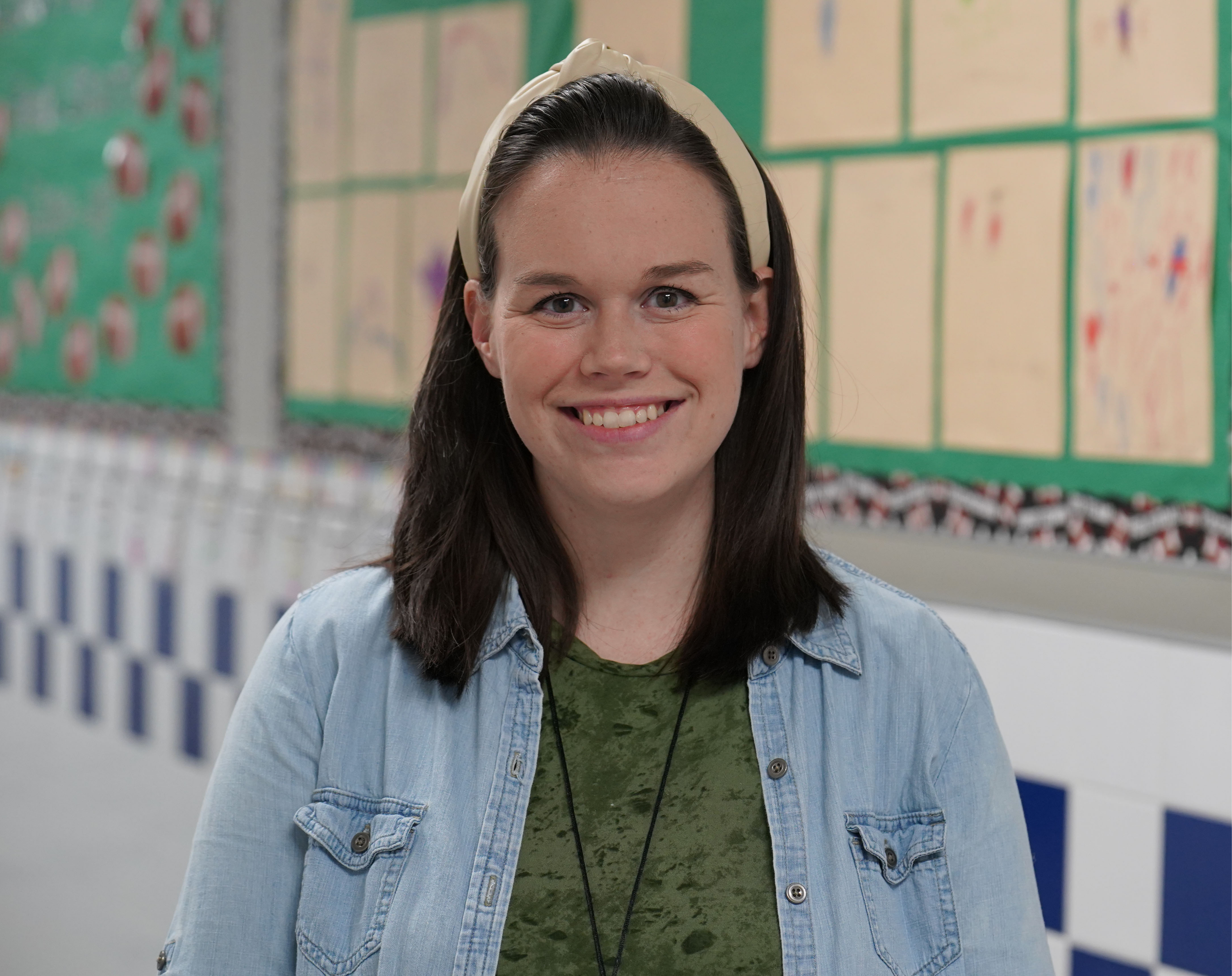 woman in a school hallway wearing a green shirt and denim shirt over it