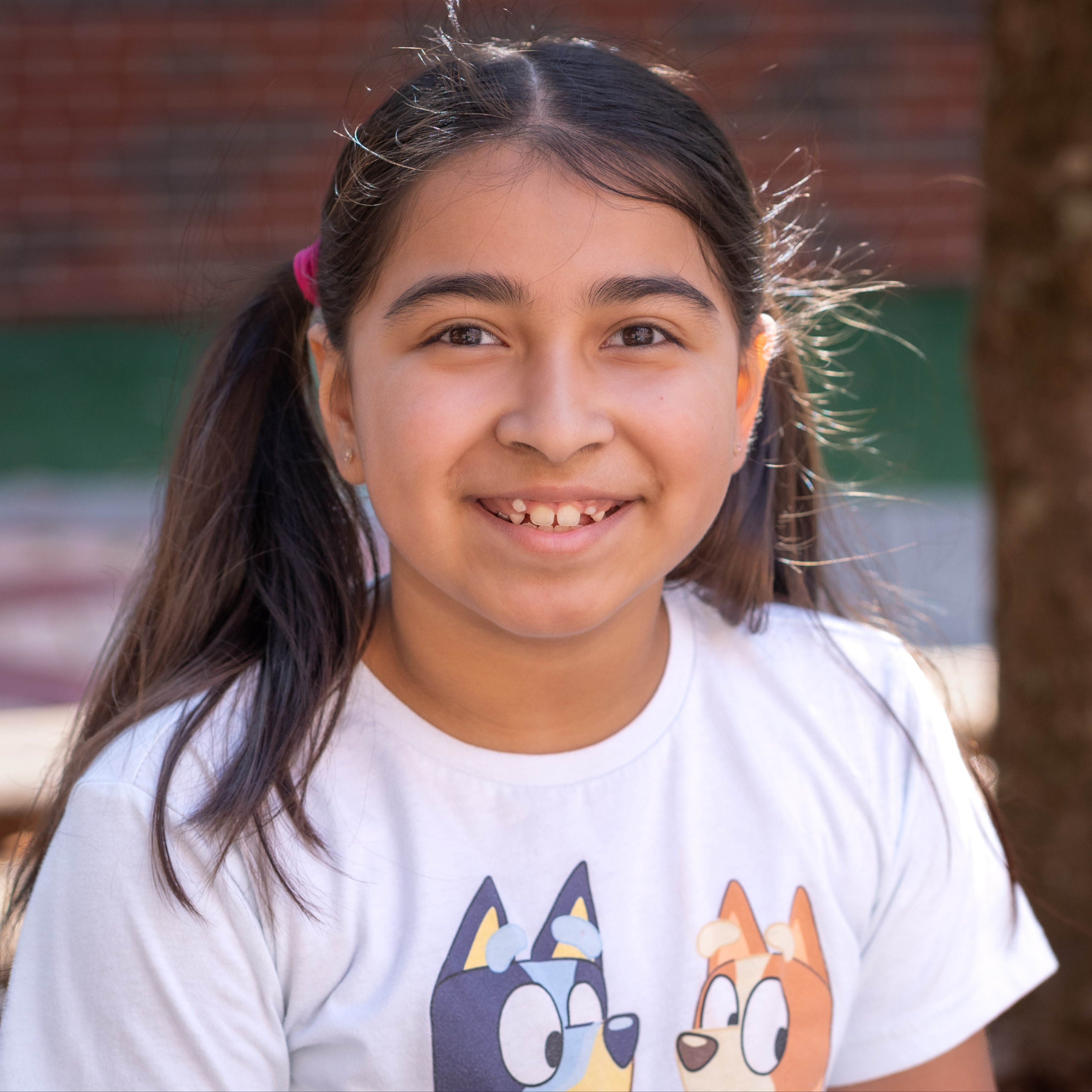 elementary age girl wearing pigtails and a white t-shirt