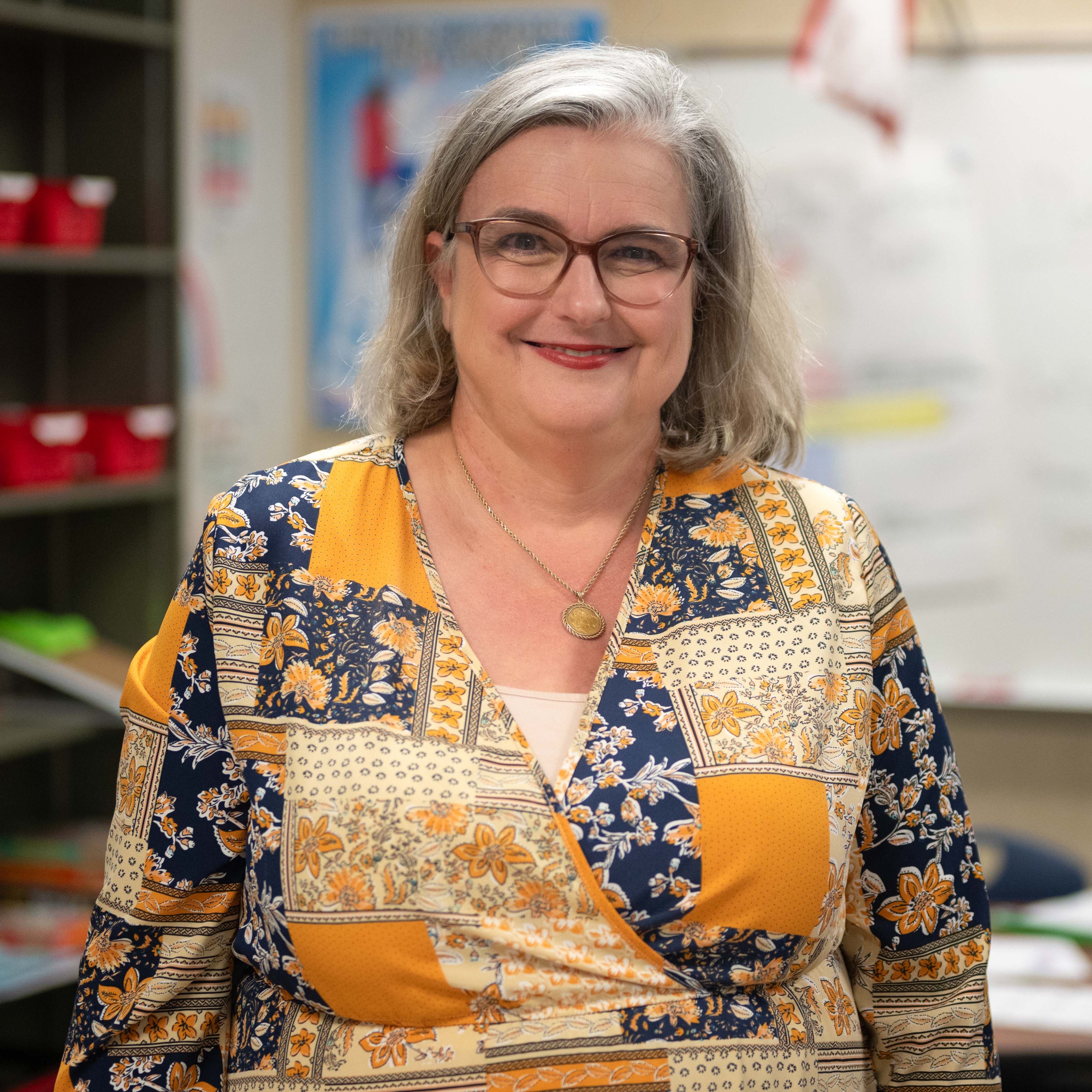 woman wearing yellow print blouse in classroom