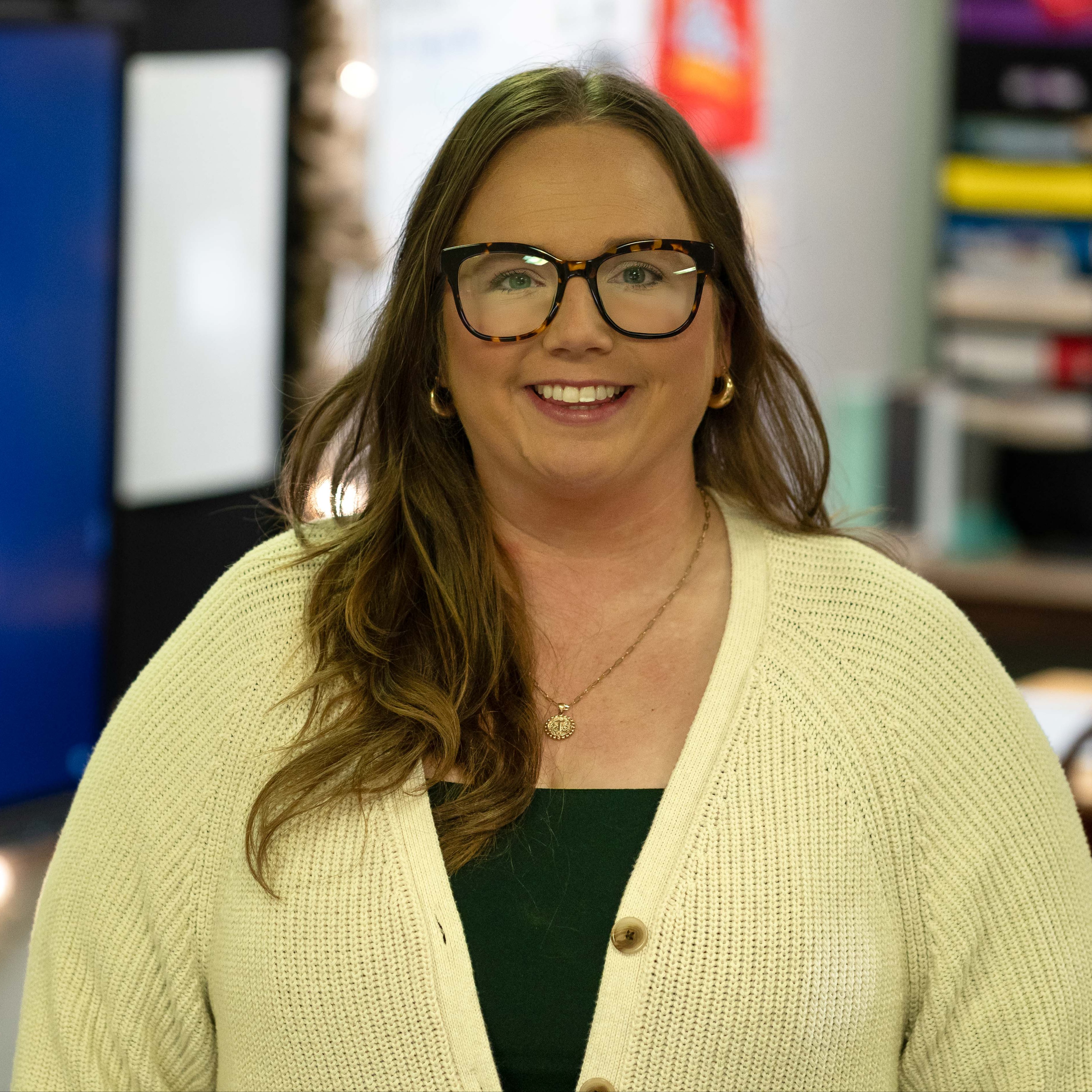 woman with long brown hair and glasses smiling
