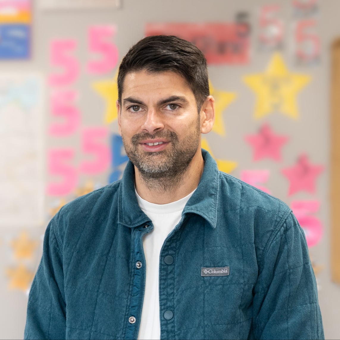 man with dark hair and beard standing in hallway