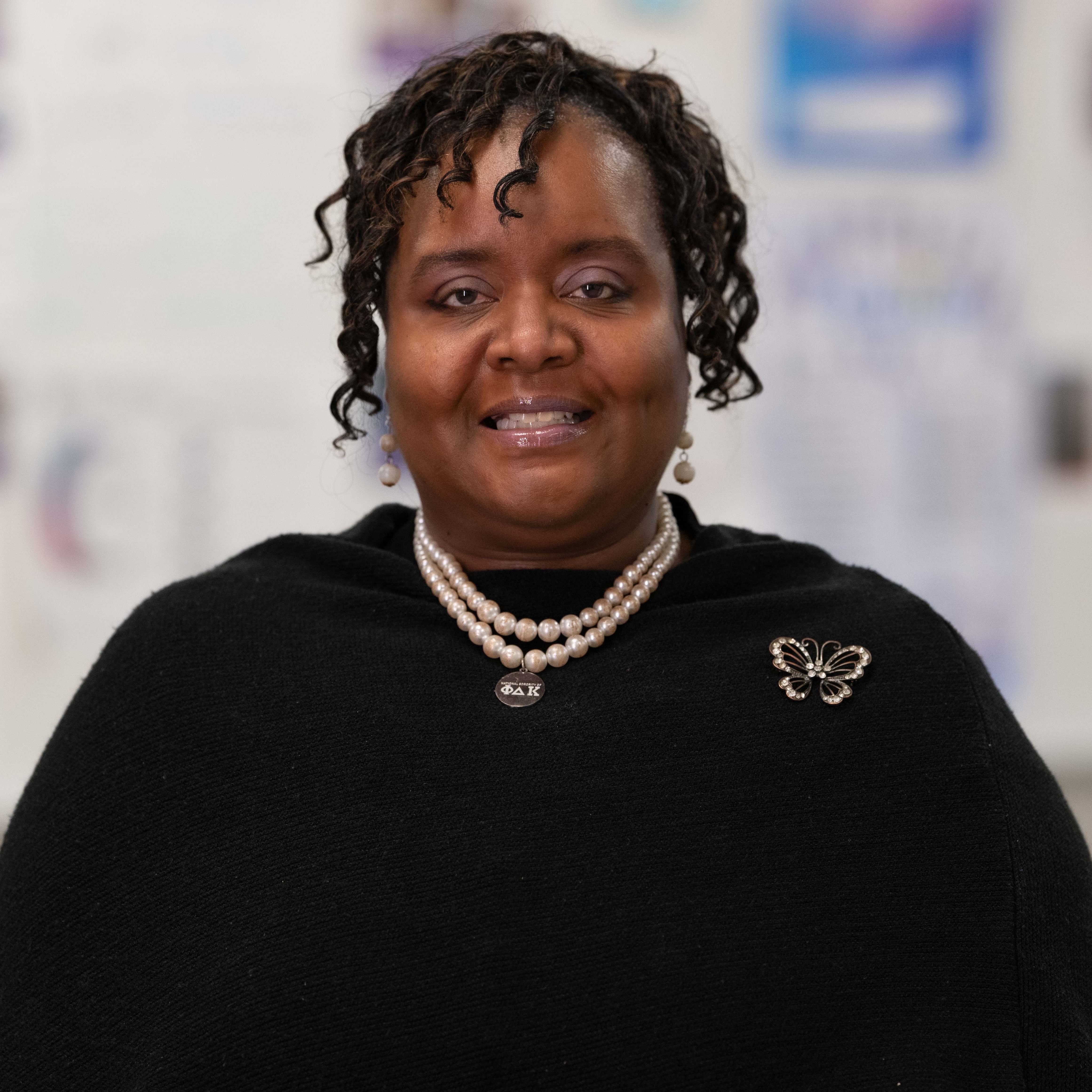 African American woman wearing a black shirt and pearl necklace