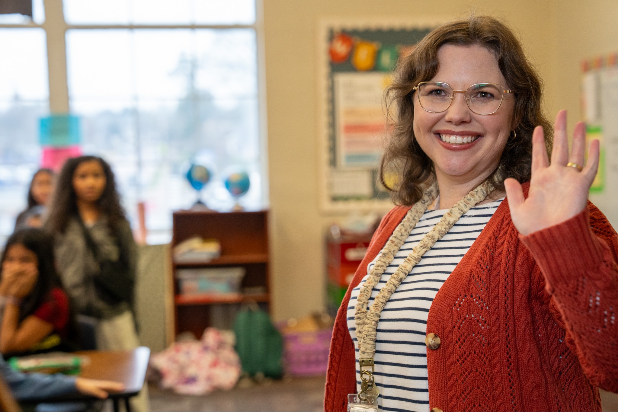 woman waving and smiling from classroom door