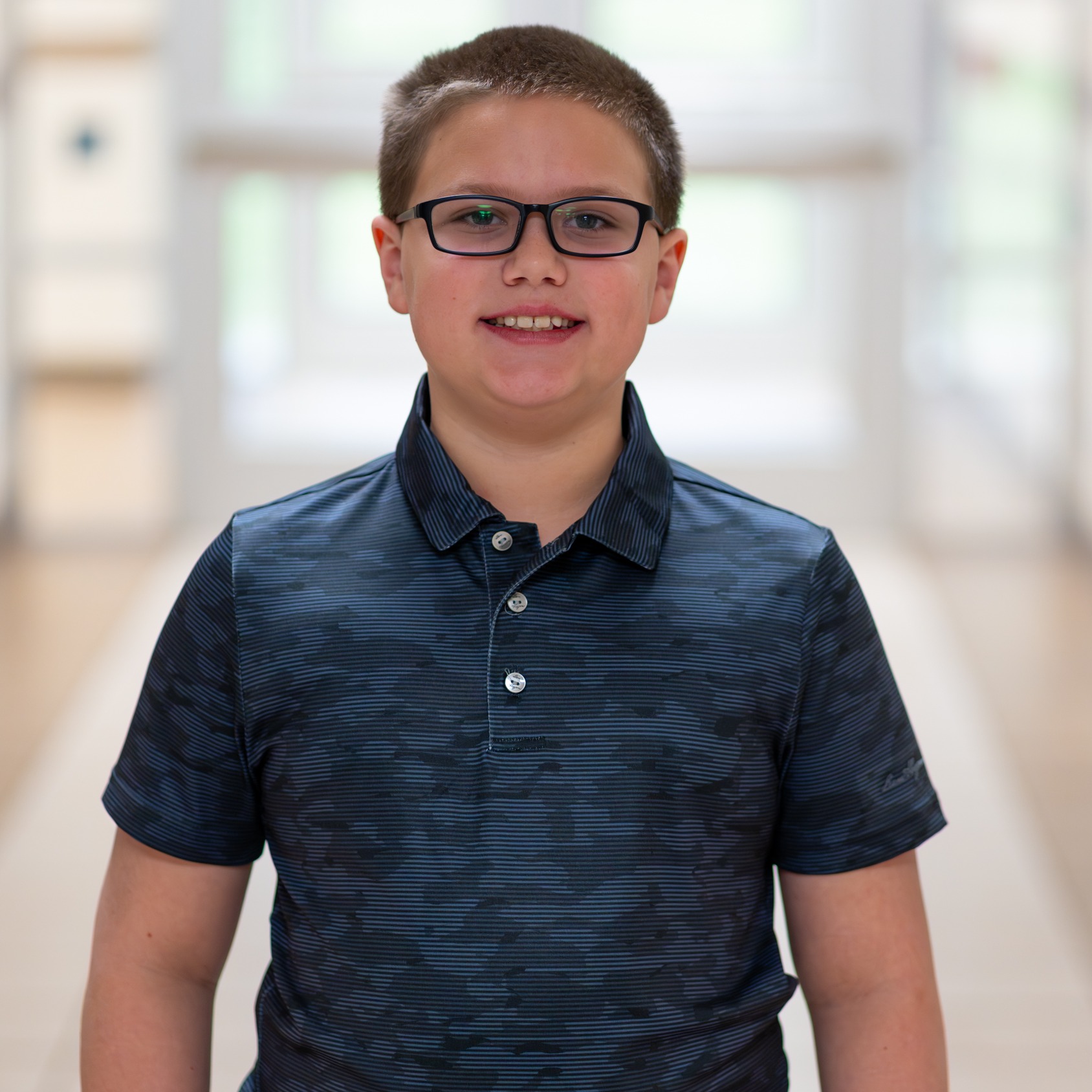 elementary age boy wearing glasses standing in hallway