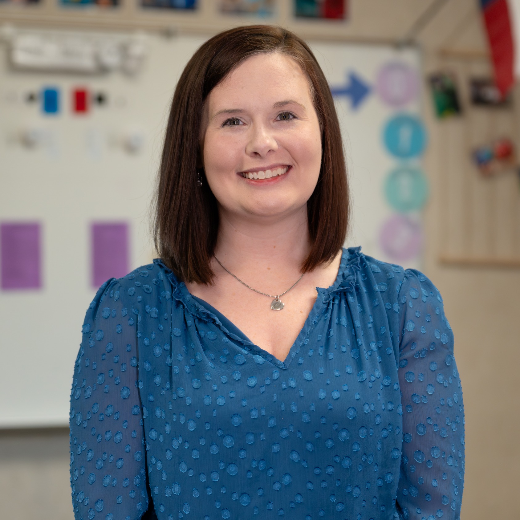 woman with shoulder length brown hair standing in her classroom