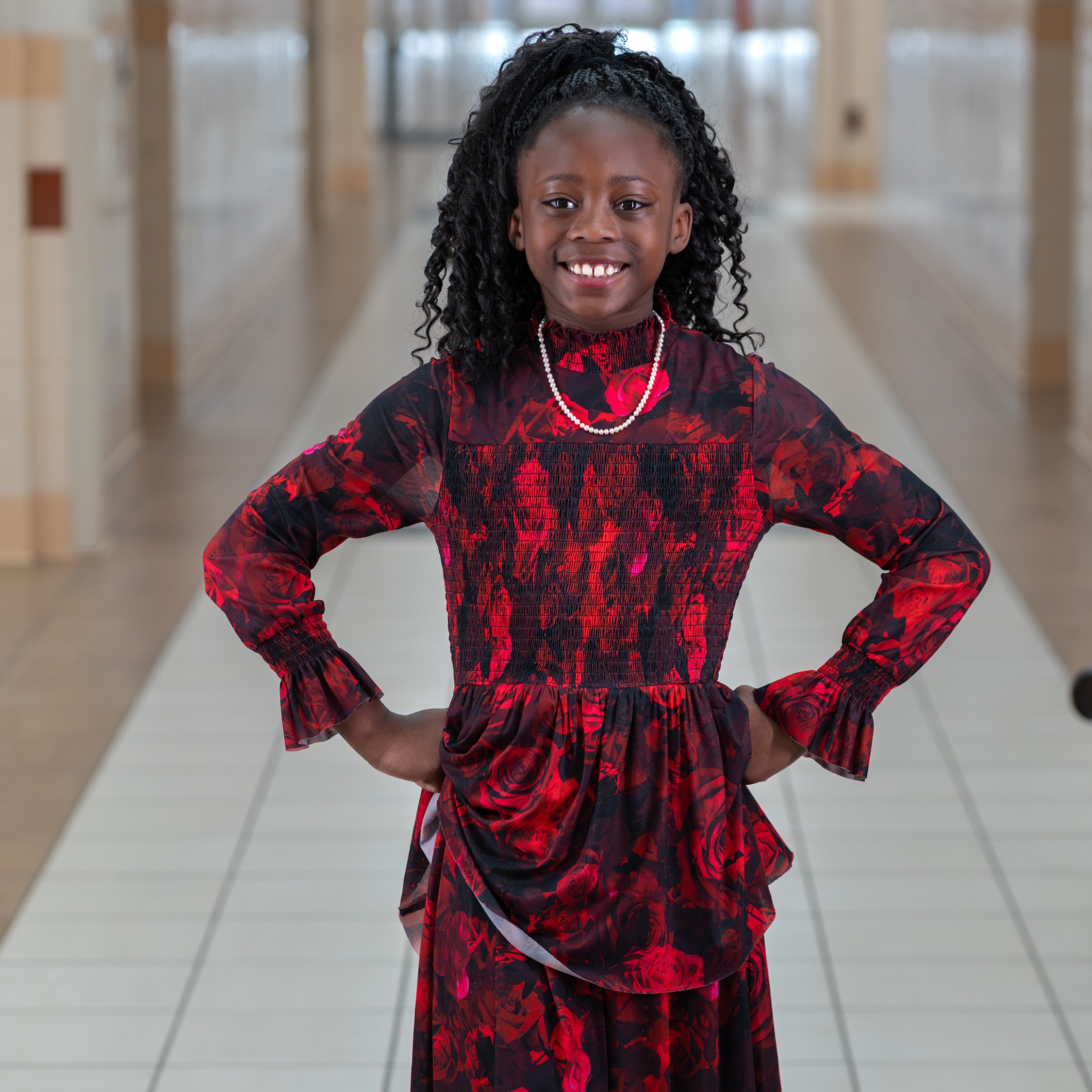 elementary age girl standing in school hallway with hands on hips