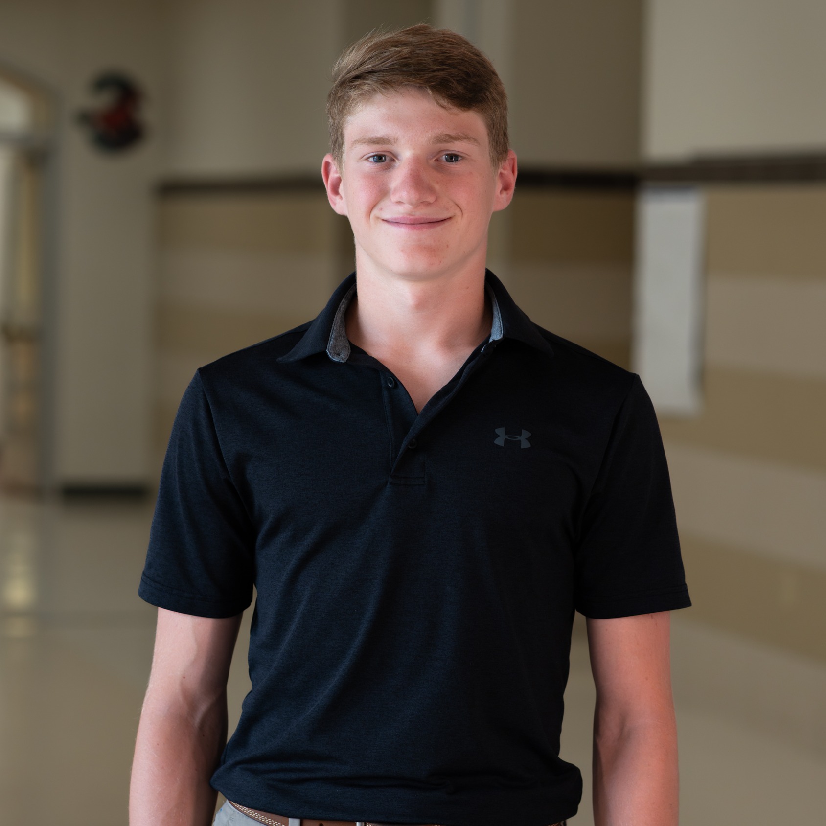 teen boy standing in school hallway