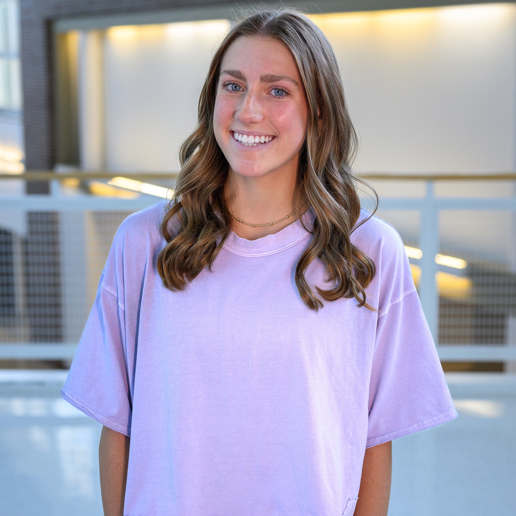 teen girl wearing pink tee standing in school hallway