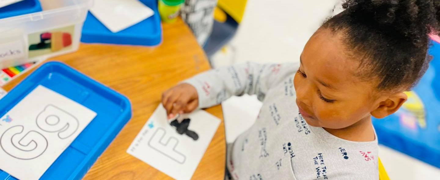 child playing with letters and playdough