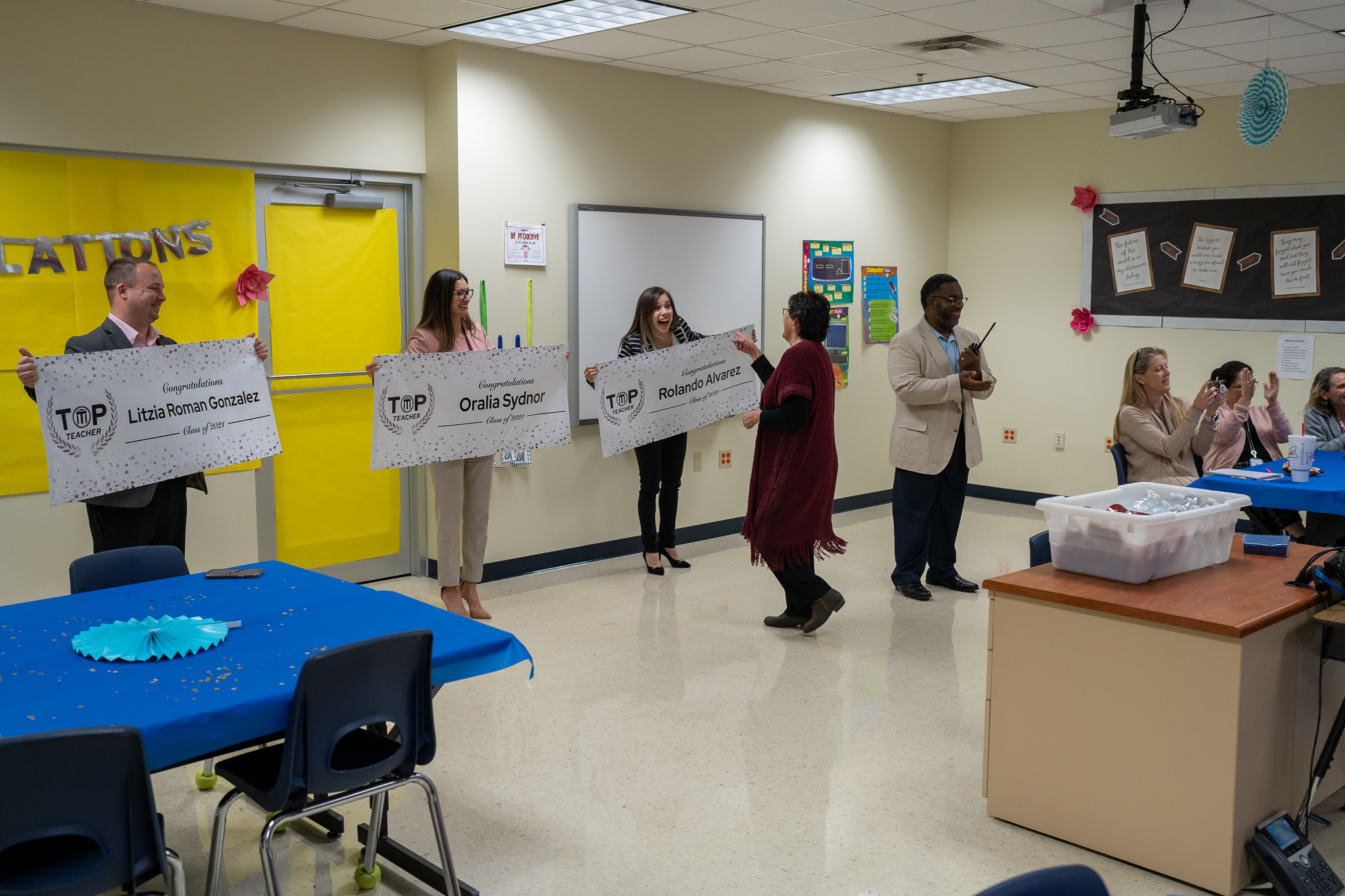 teachers surprised in front of colleagues with award banner