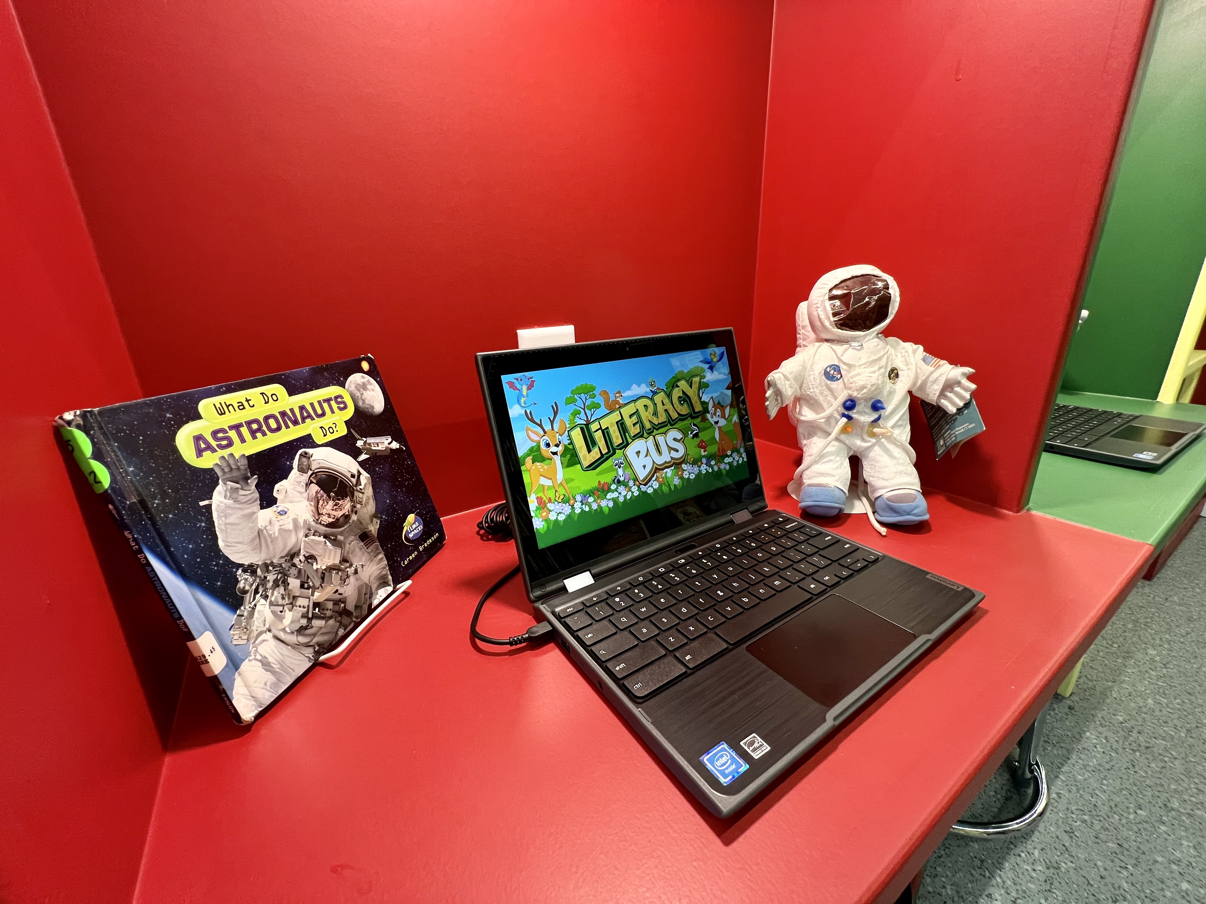 laptop, book and stuffed astronaut on a red shelf
