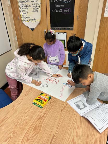 Students writing on a poster board with markers