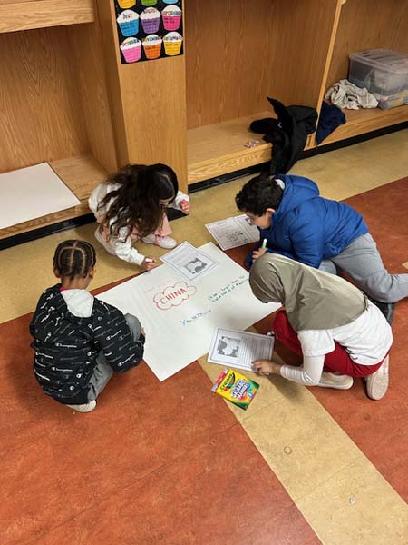 Students writing on a poster board with markers