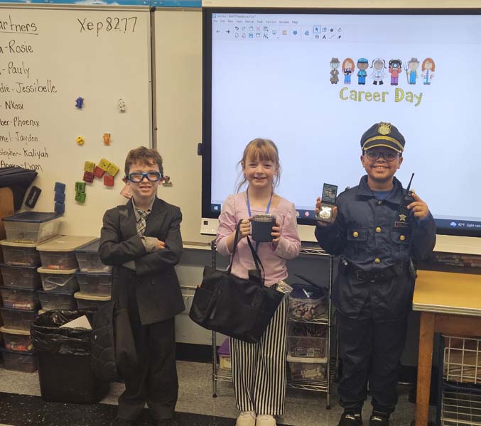 Three students dressed up (left: student dressed up in a suit and tie; middle: student dressed as a teacher; right: student dressed as a police officer)