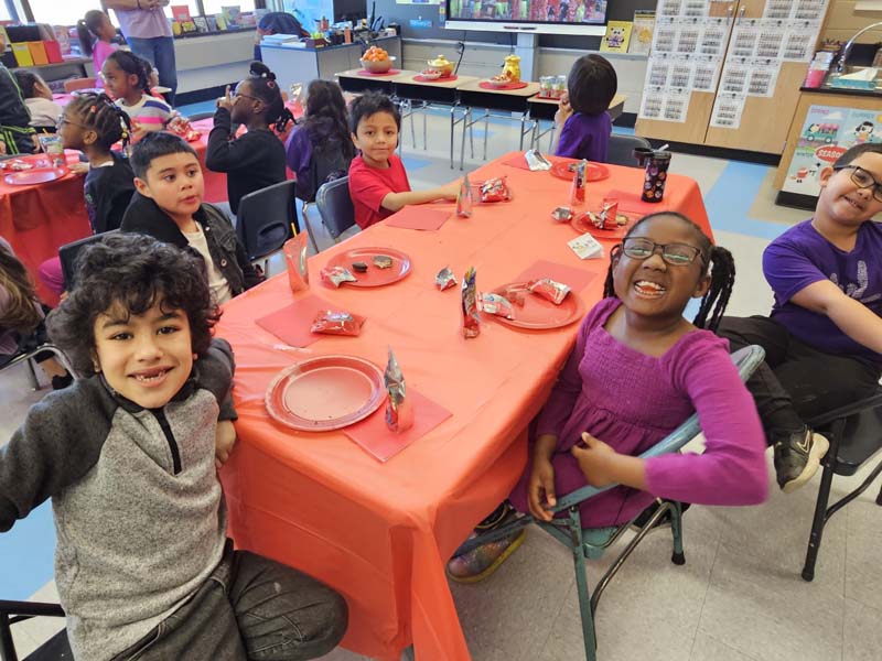 Students sitting in their classroom eating food at tables.