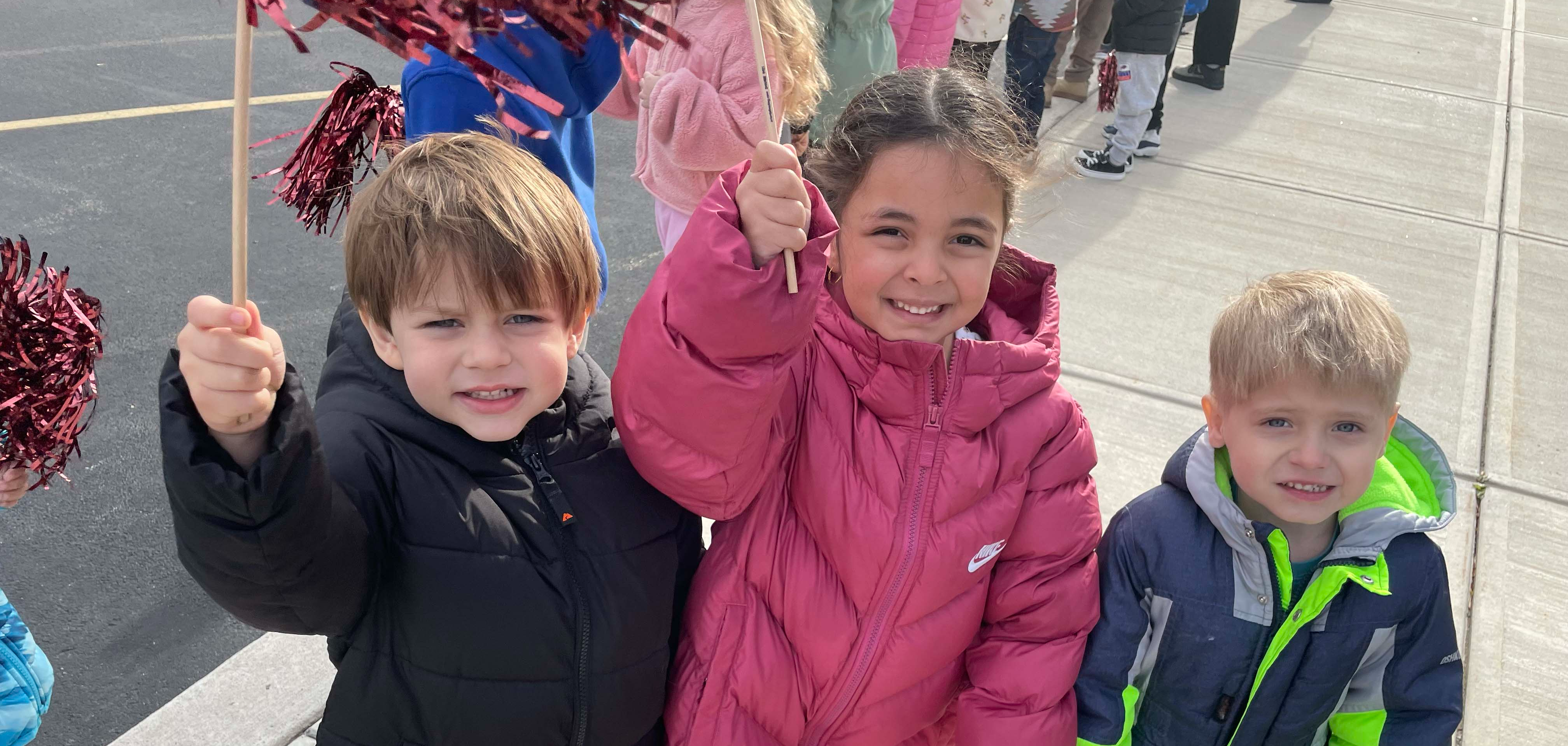 students waving pom poms and smiling at the camera