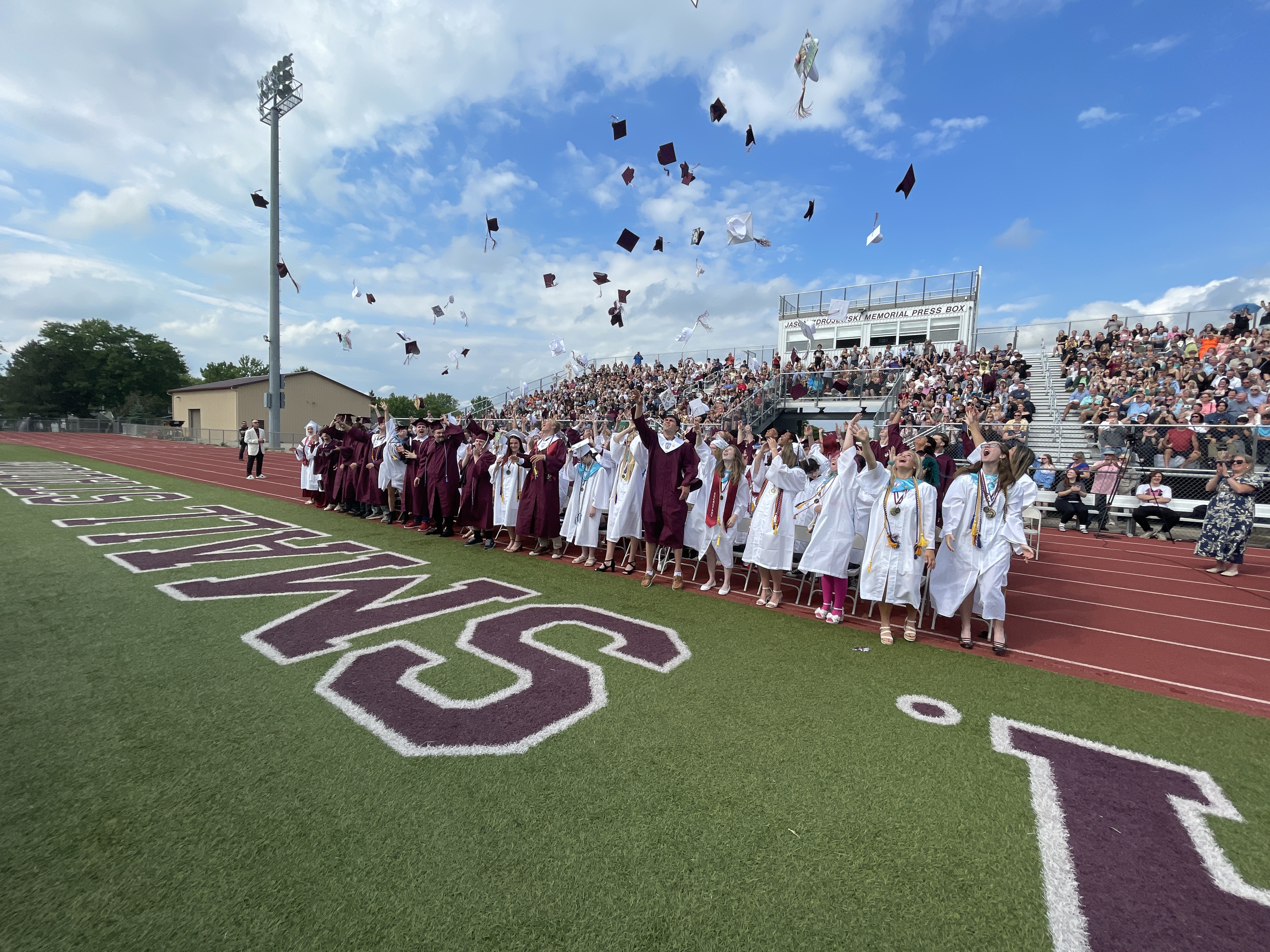 class of 2026 throws caps in air at graduation 