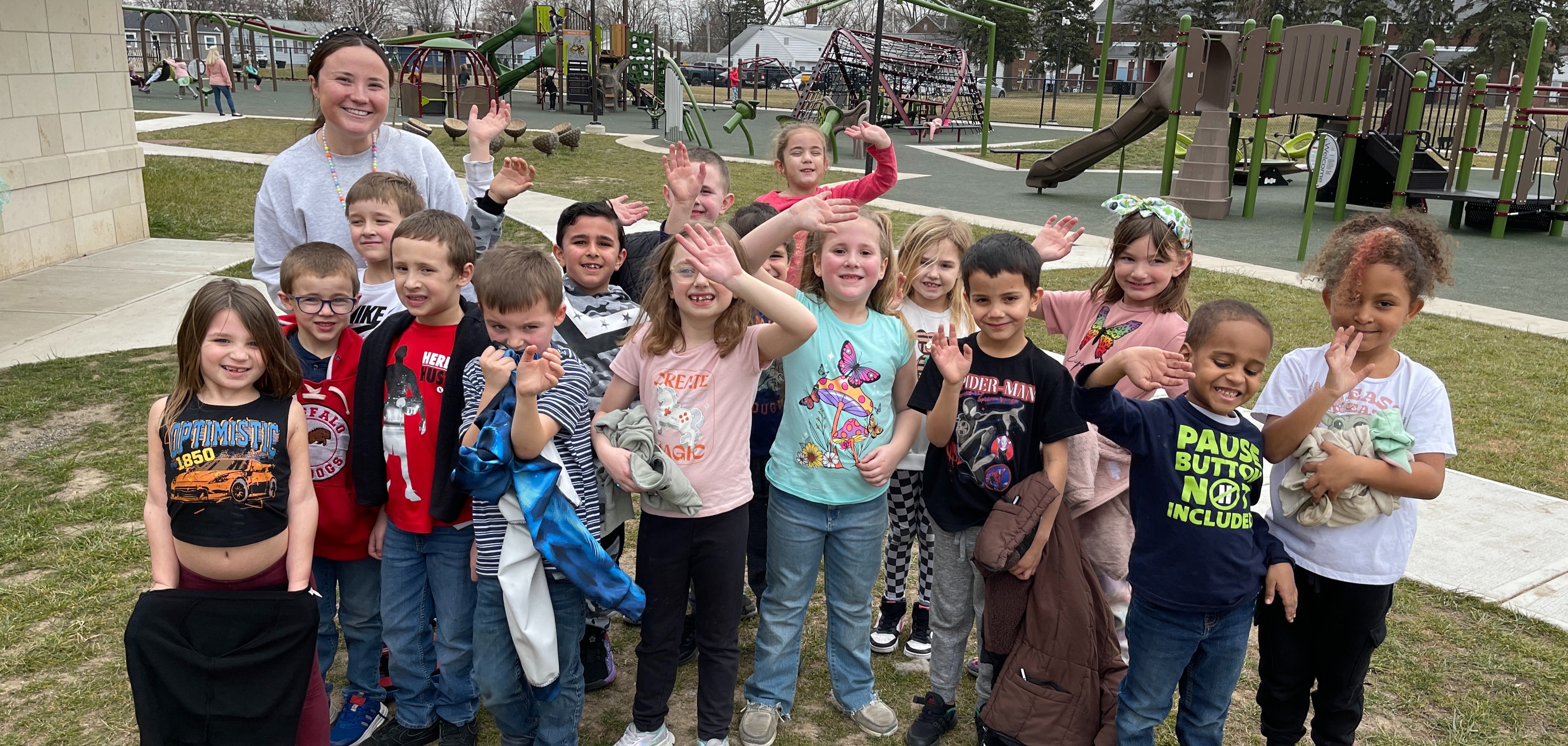children smiling and waving on playground