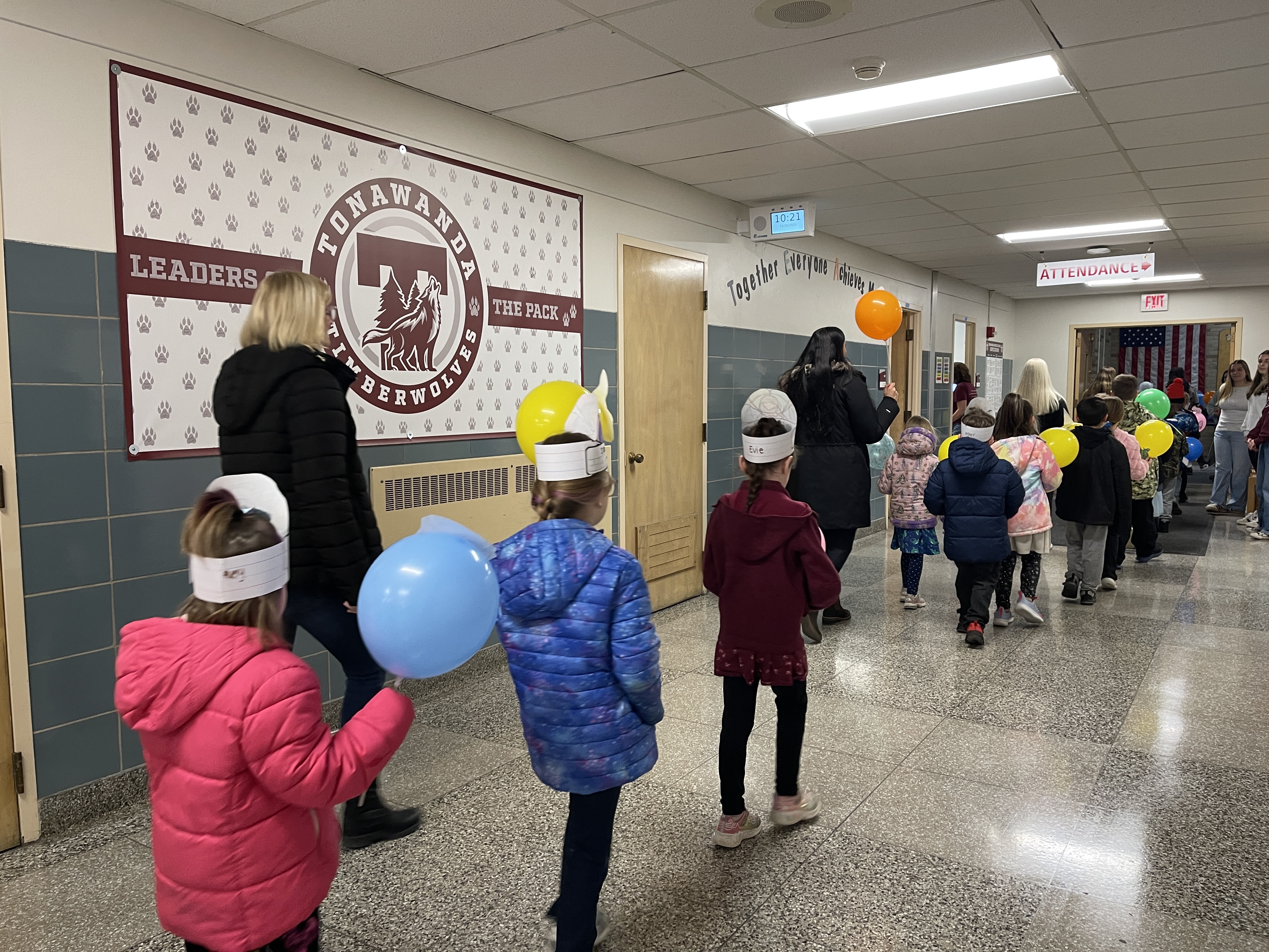 students marching in parade through halls of school with balloons