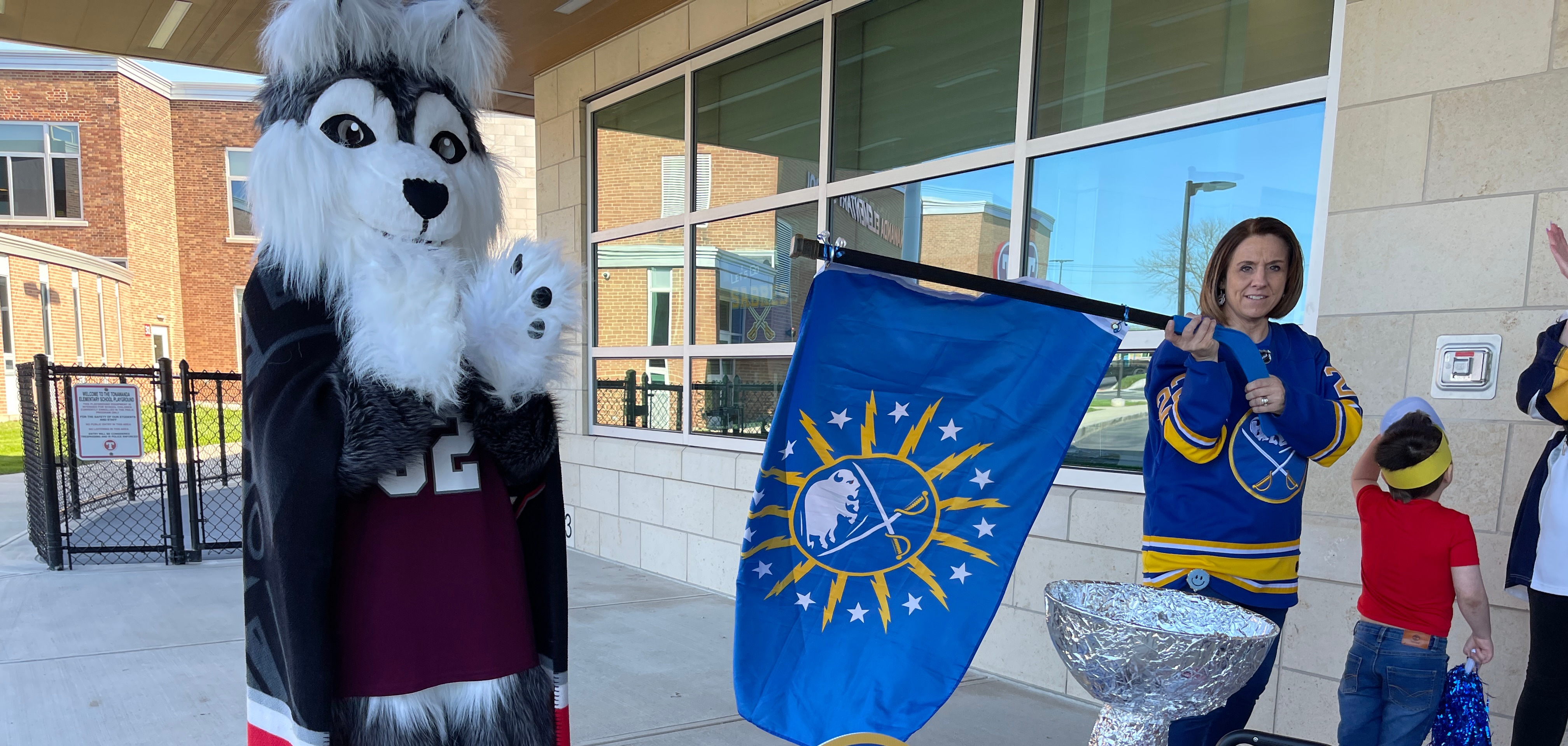 teacher waves sabres flag with timberwolf mascot and homemade stanley cup in foreground