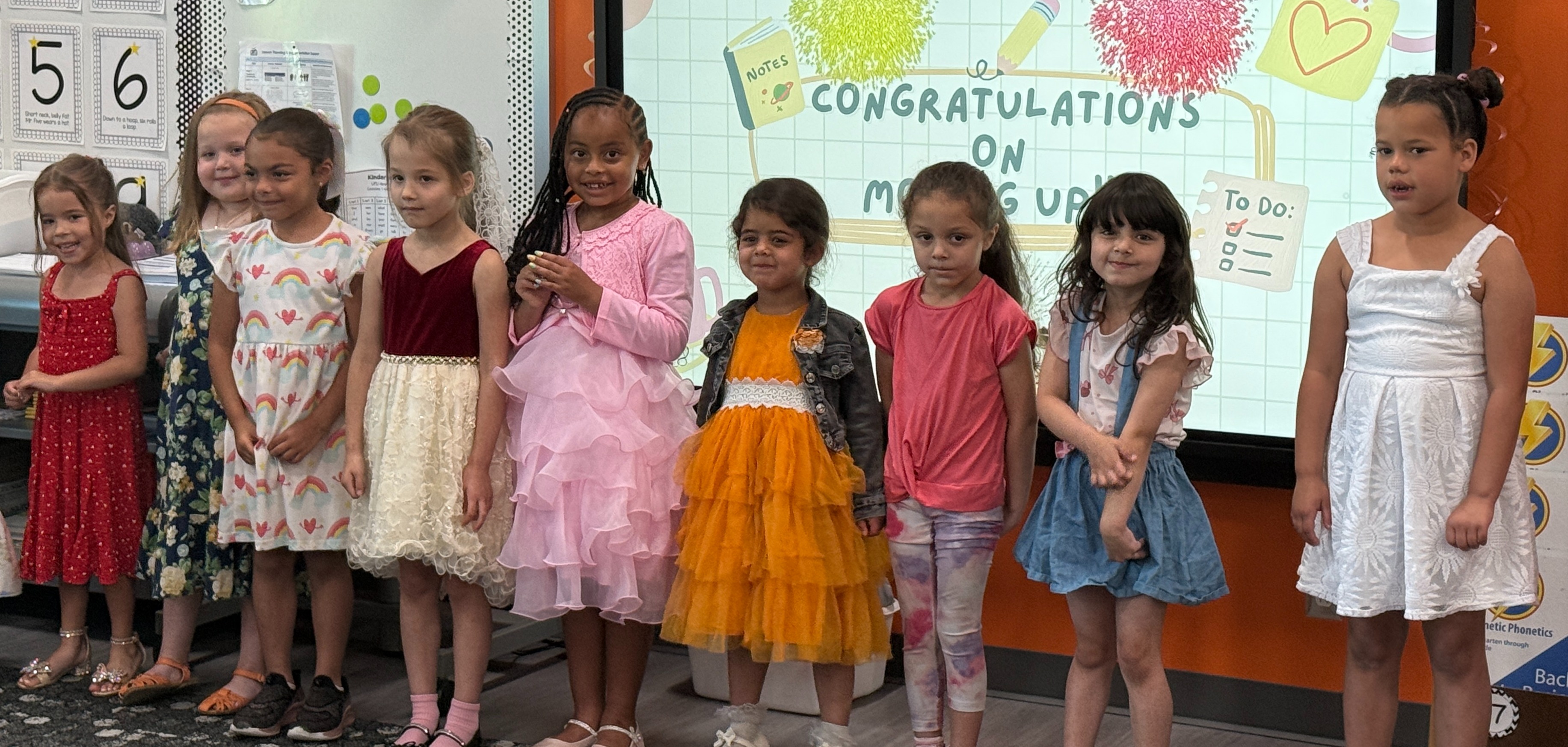kindergarten students line up in front of classroom dressed up for celebration