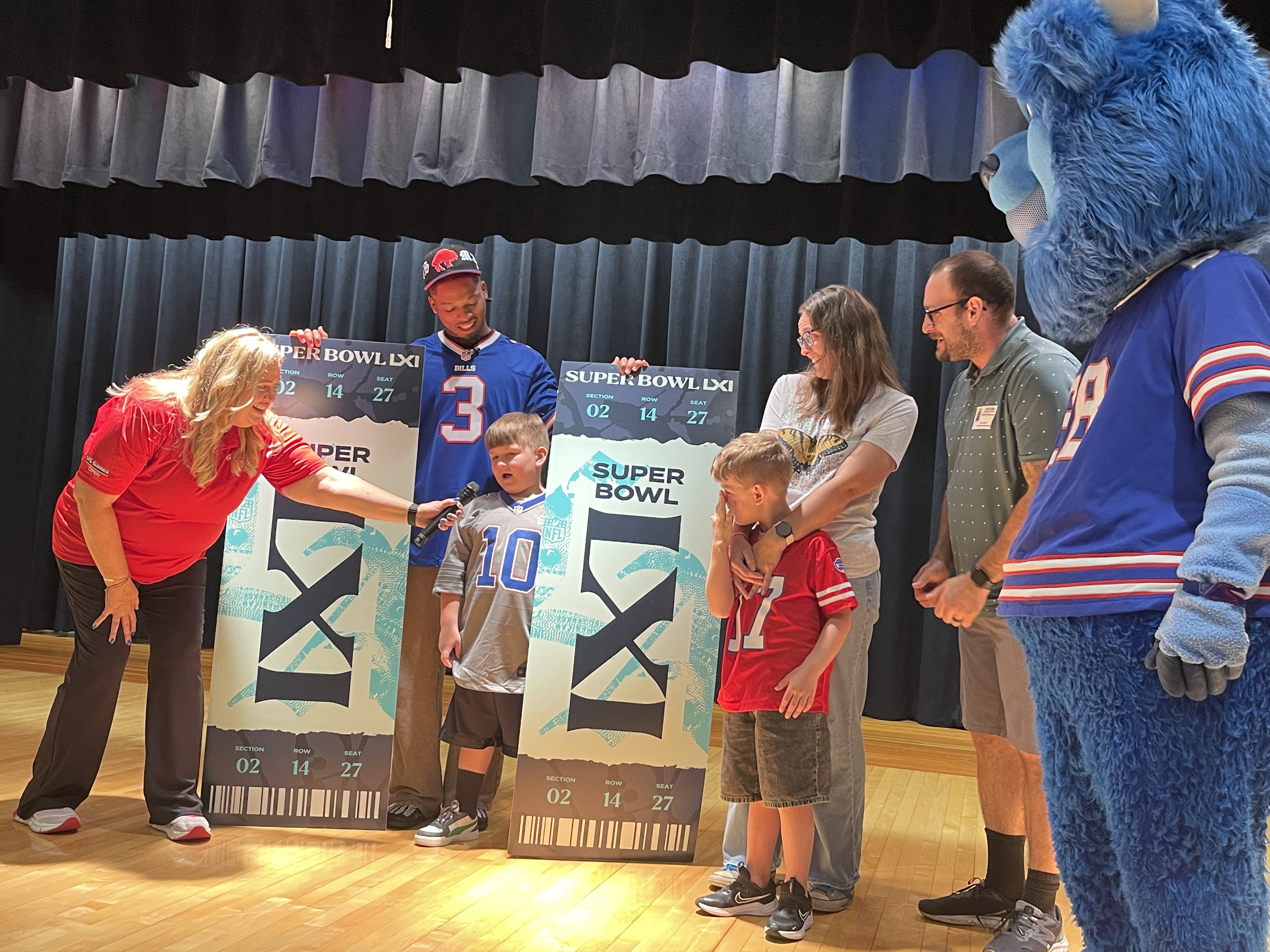 student and family pose on stage with superbowl tickets and damar hamlin