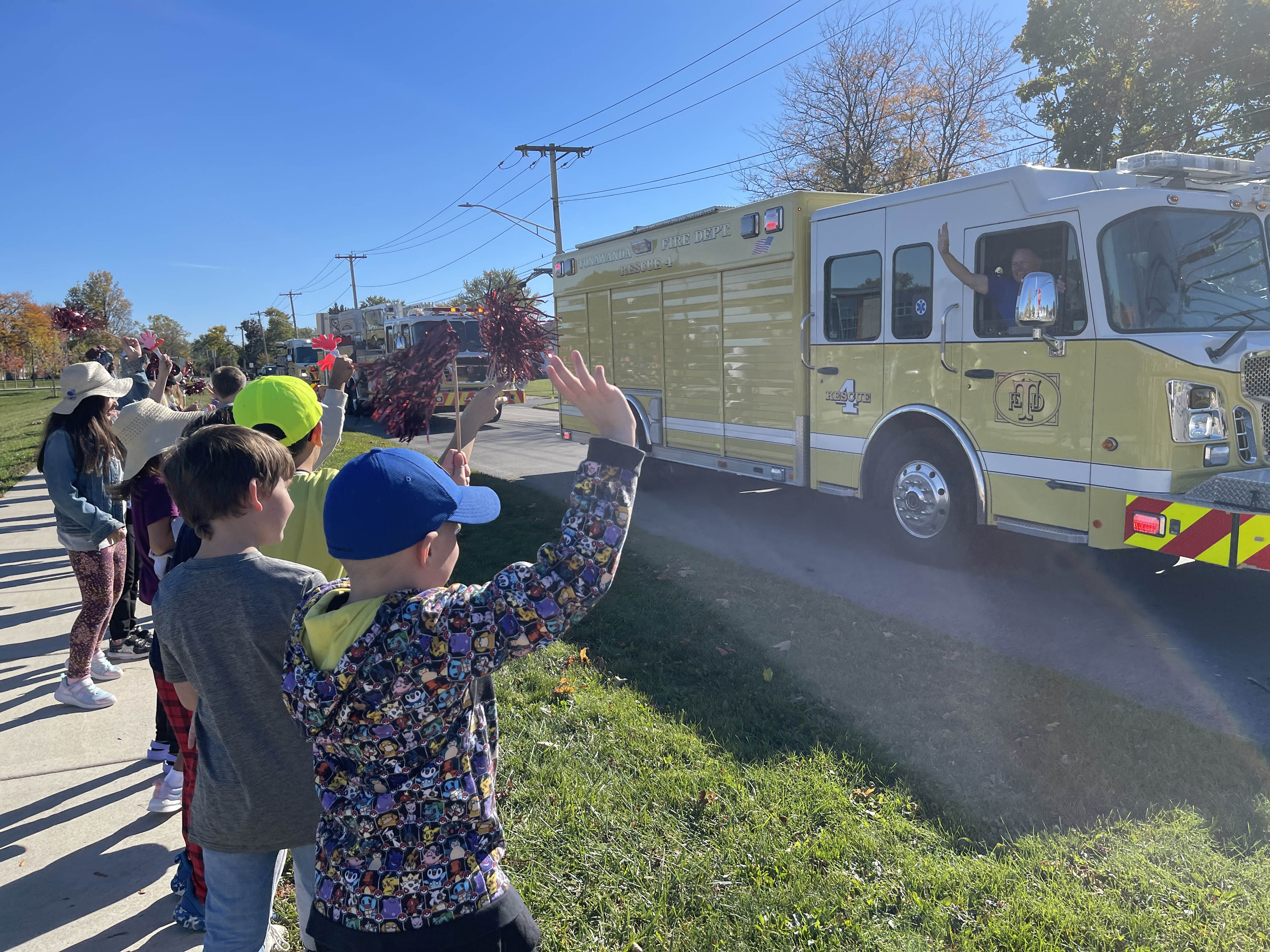 children wave at firetruck driving by