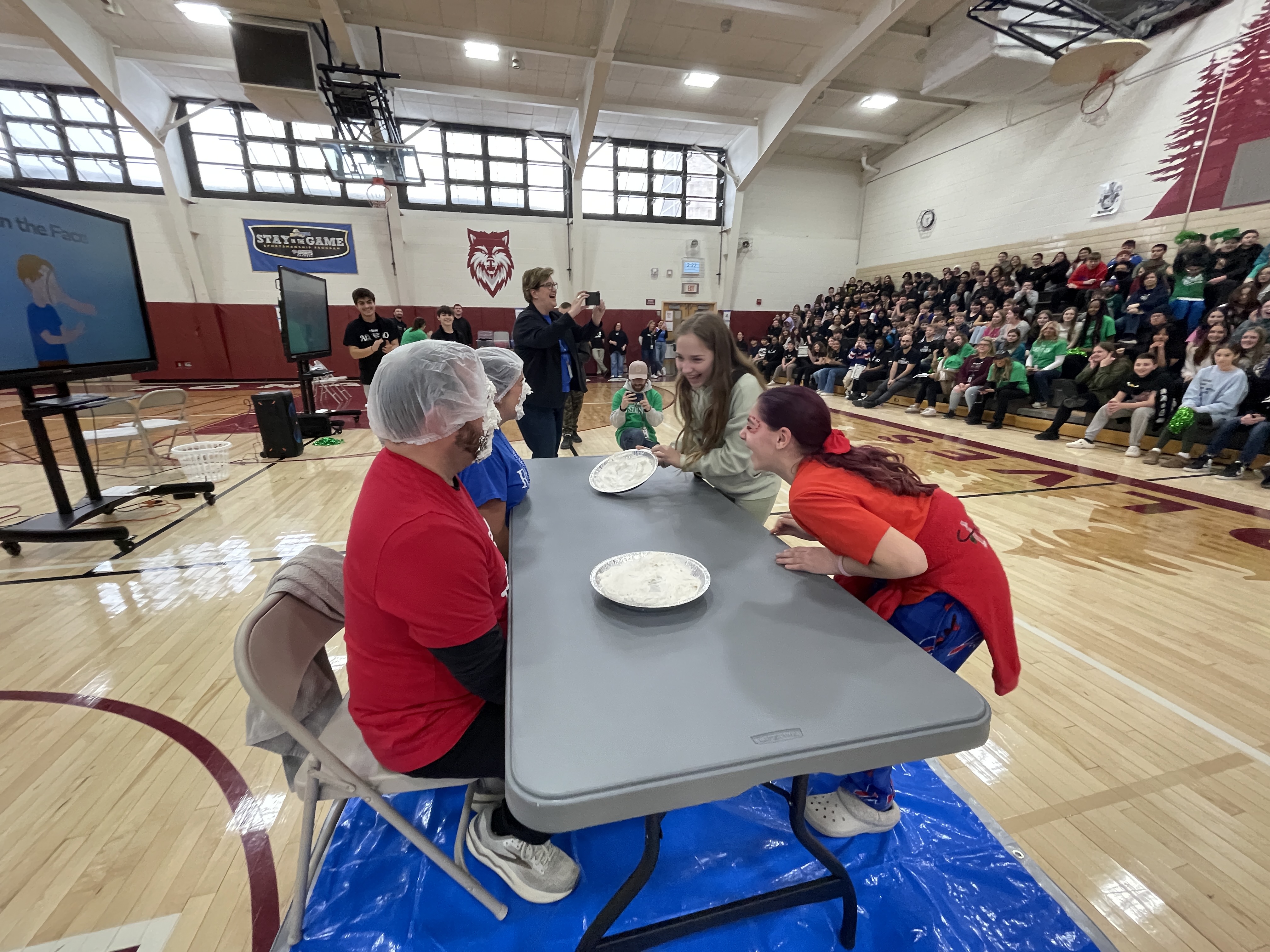 students laugh at a table after smashing pie in admins faces