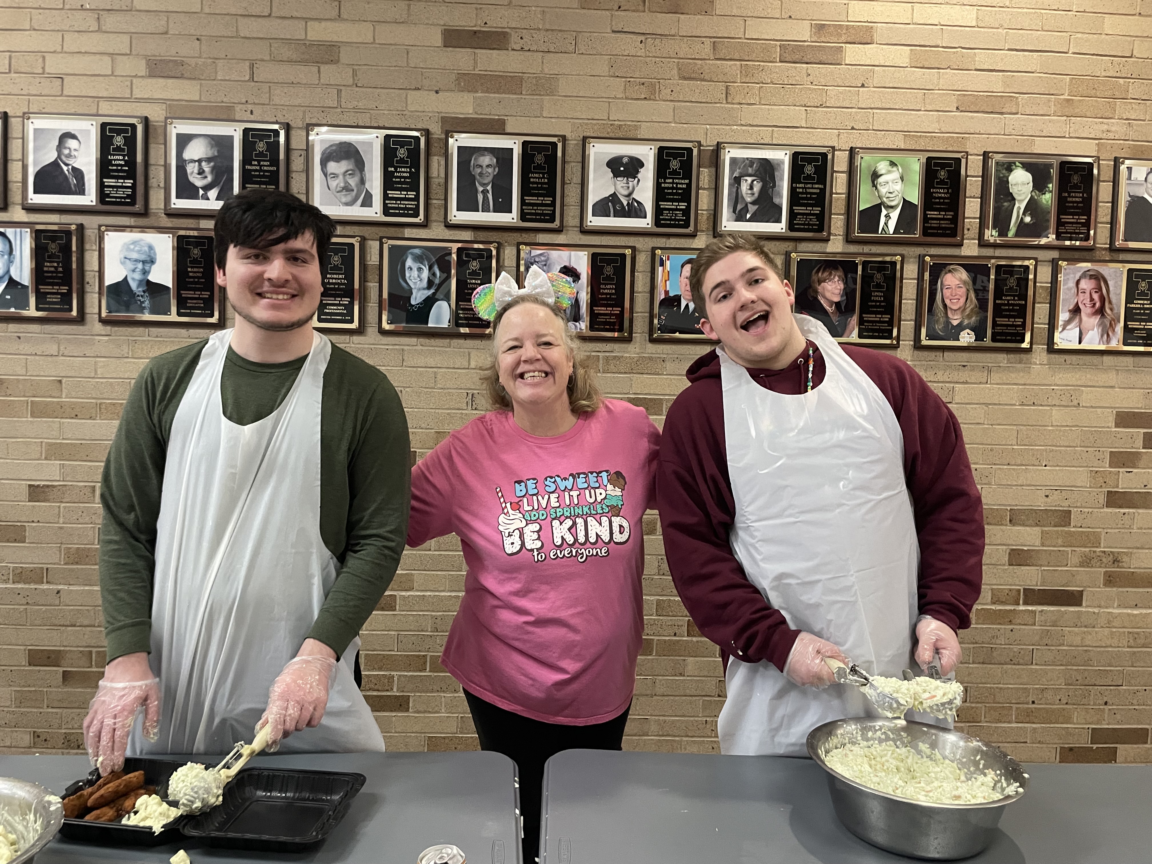 teacher and students pose as they serve fish fry dinners