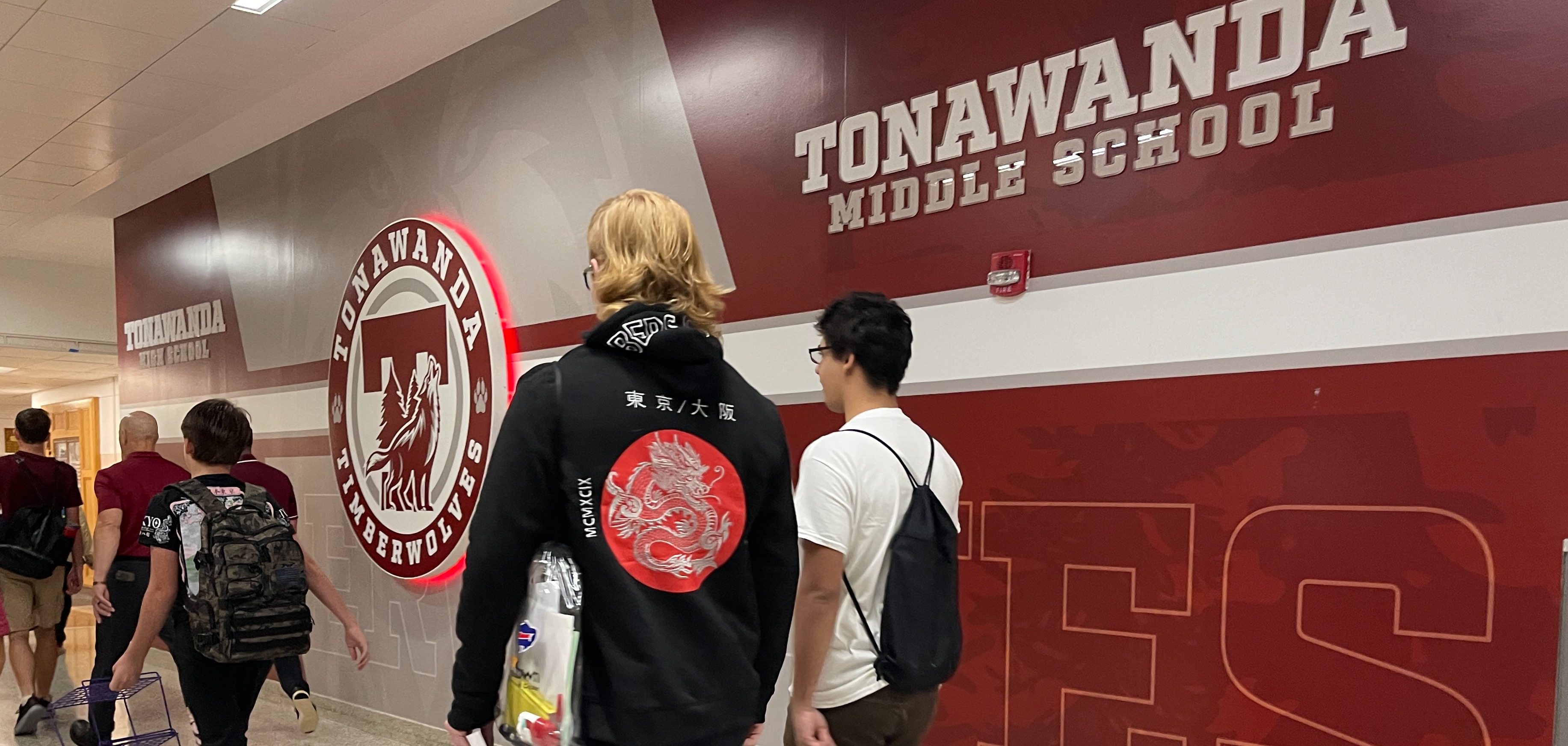 students walk past the TMS sign and logo as they enter schools for new year