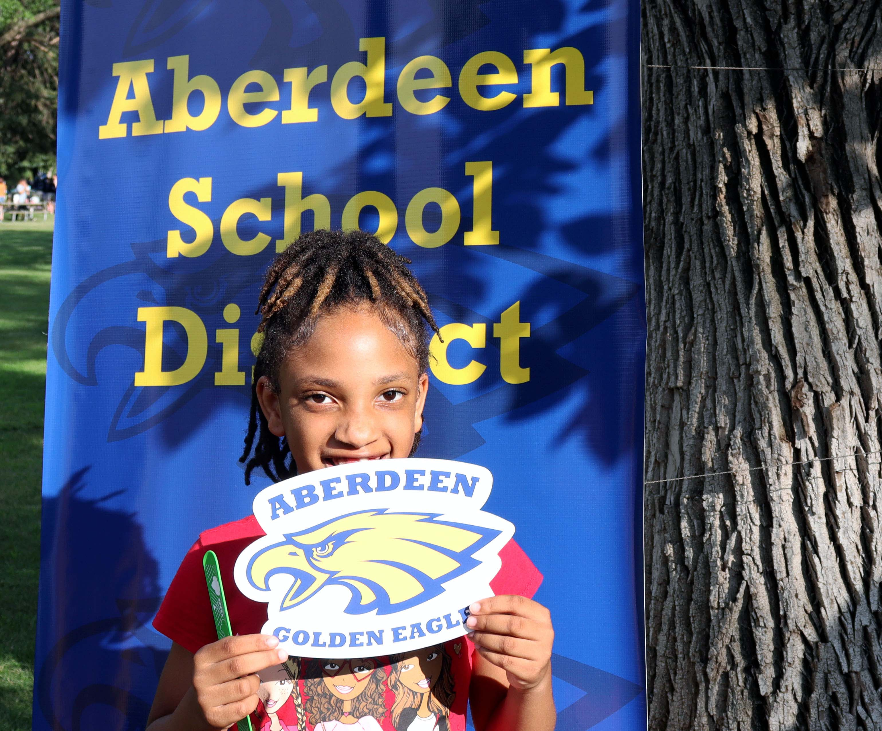 Student in the community in front of an Aberdeen School District backdrop
