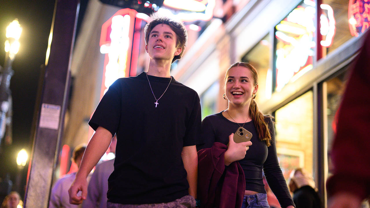 A boy and a girl walk the neon-lit streets of Nashville on the JEA/NSPA field trip.