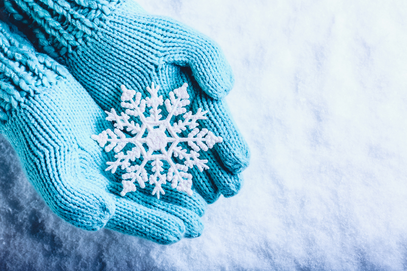 Photo of blue mittens holding a snowflake