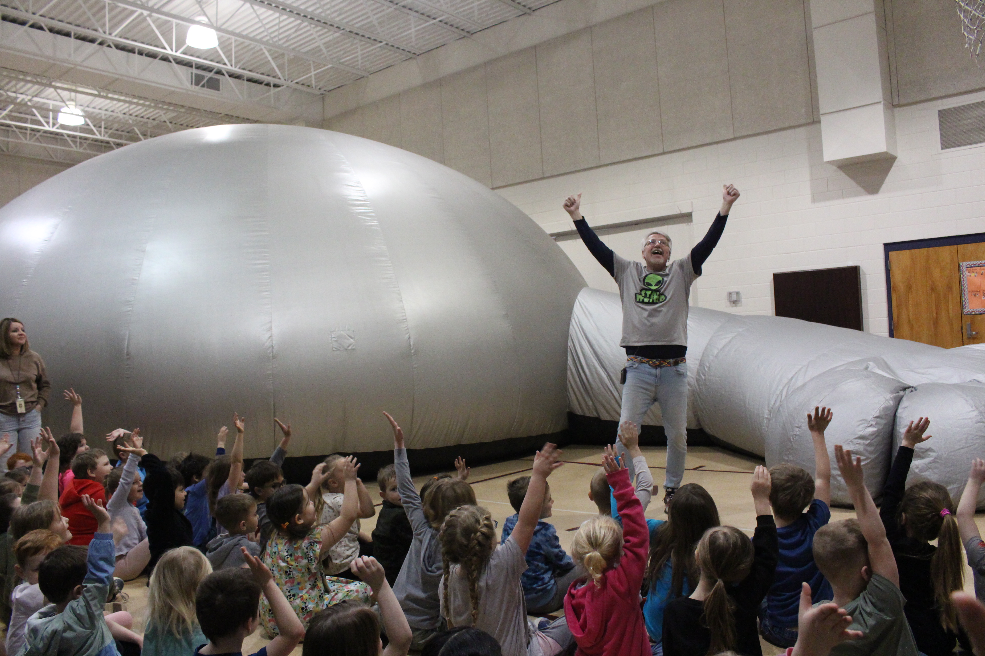 students and adult in front of inflatable planetarium