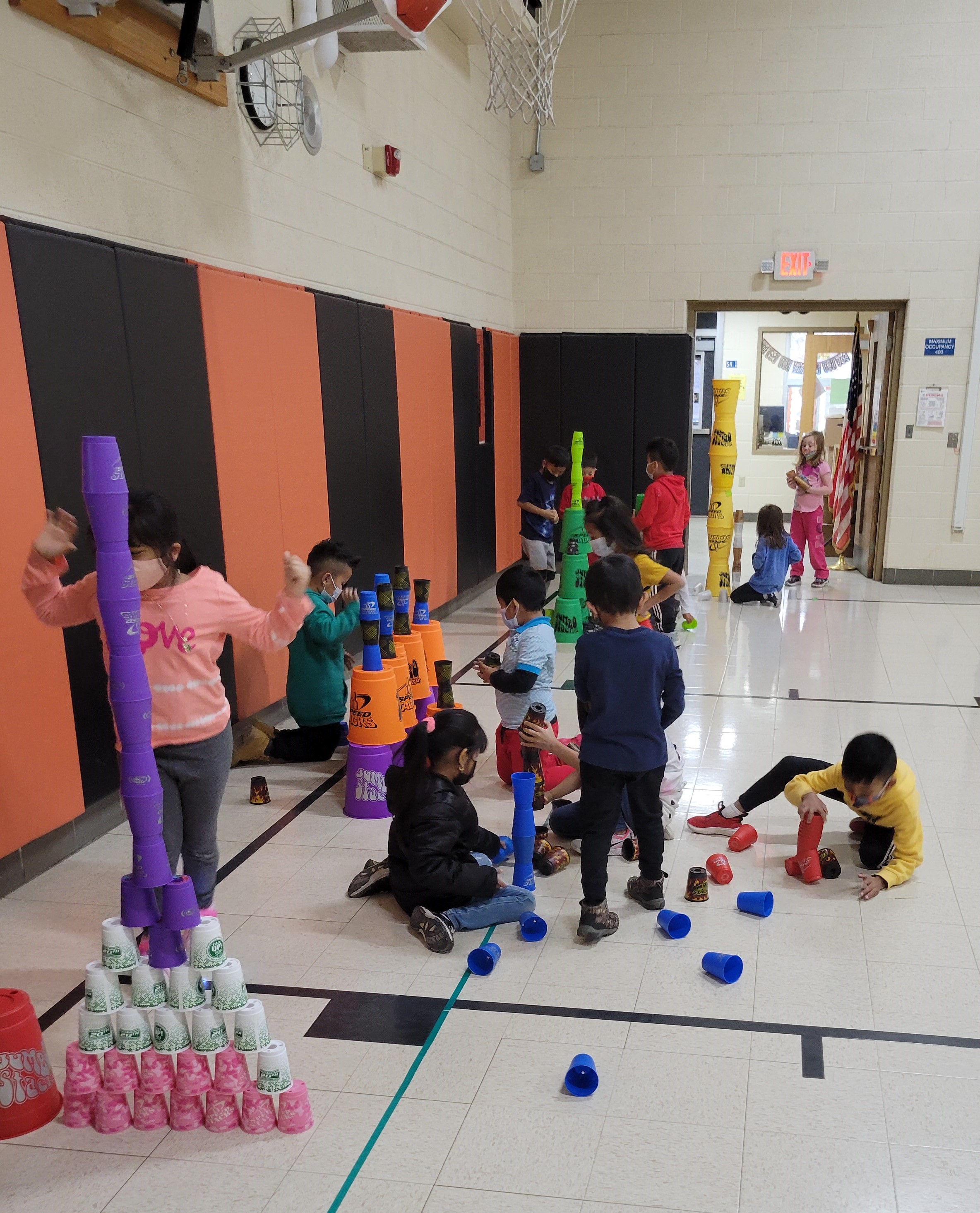 many students working on the floor stacking cups as tall as they can in single towers