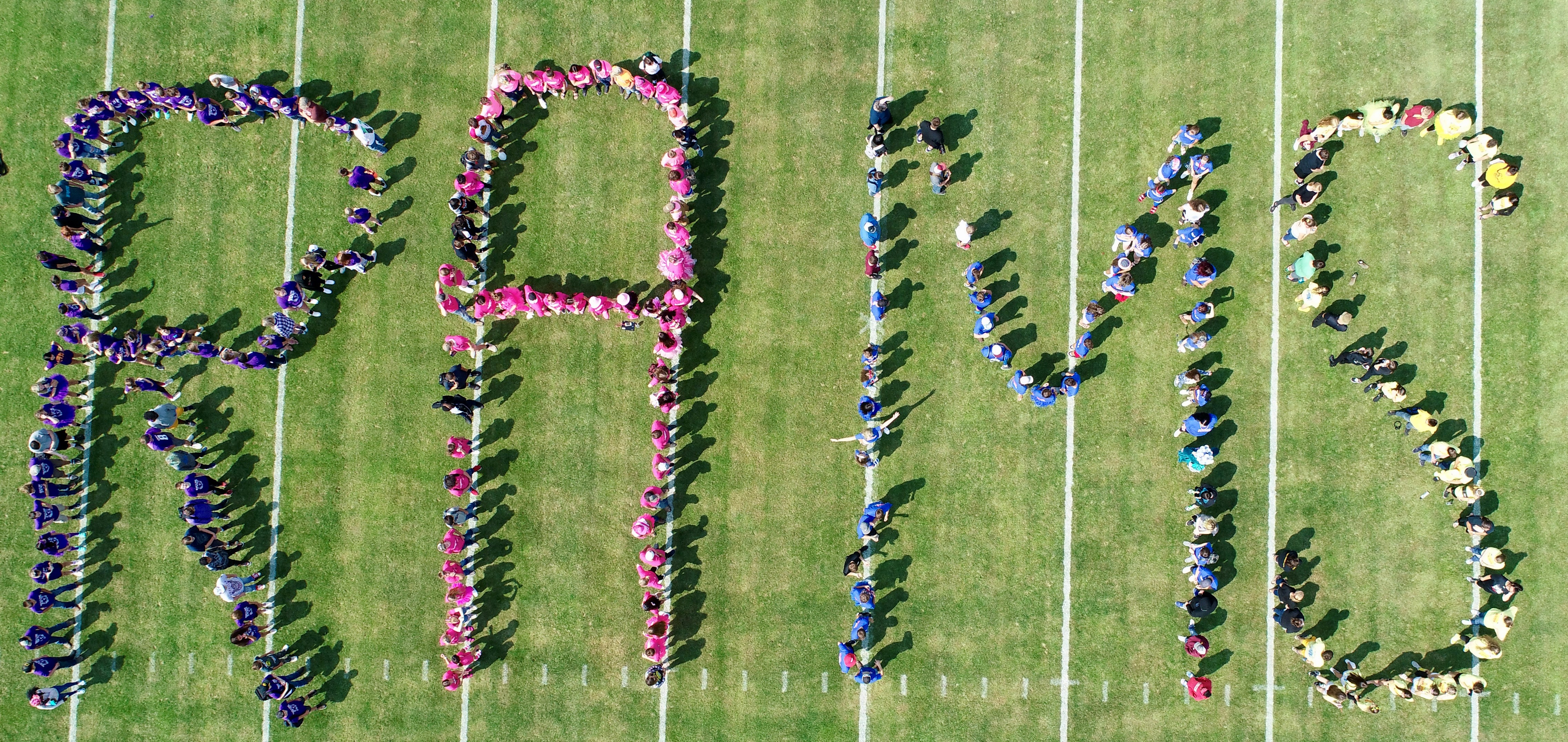 Students forming "Rams" on the football field for a drone photo.