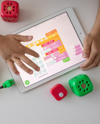 hands manipulating block coding on ipad