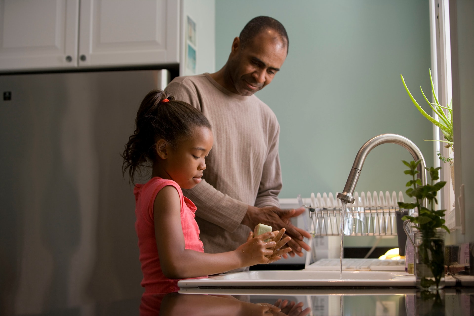 Photo of a daughter and father washing their hands.