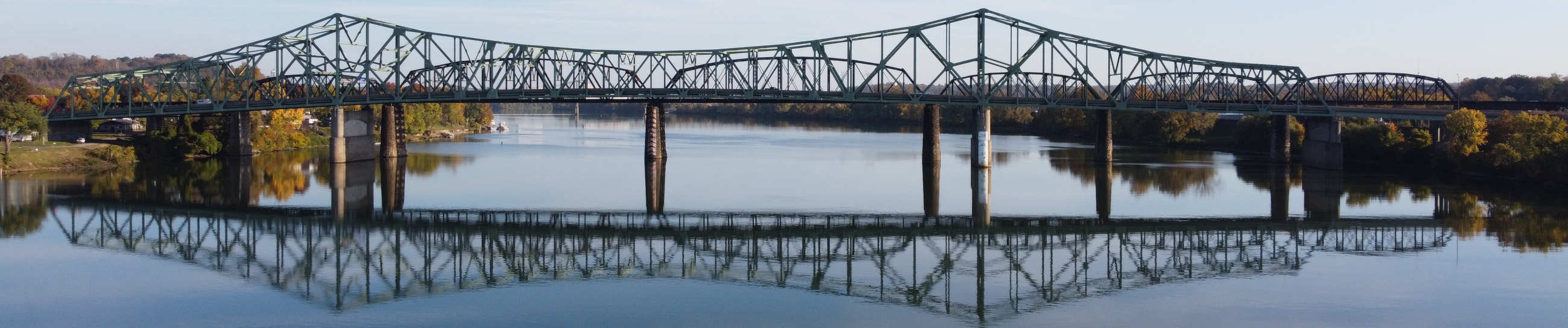 Belpre bridge connecting Belpre, Ohio with downtown Parkersburg, West Virginia -- blue skies and bridge reflection on river water below