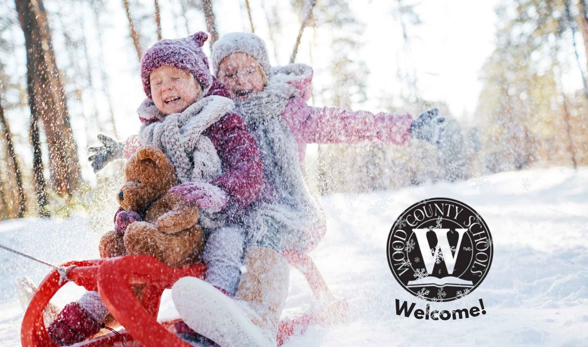 snowy winter scene with two kids on a red sled with eyes closed and big smiles