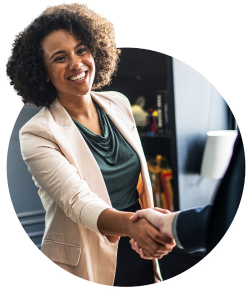 woman with a smile shaking hands with someone who is mostly not included in image