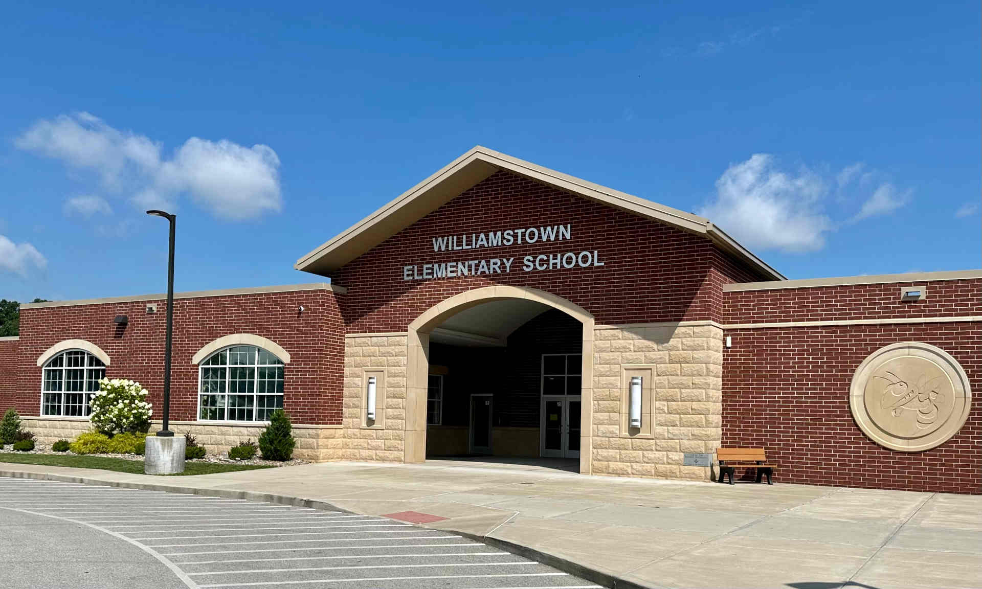 outside view of williamstown elementary school building with parking lot in front and a blue sky with limited clouds